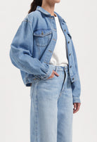 Light blue denim jacket and high-waisted jeans, featuring a casual fit, styled with a white T-shirt for a relaxed look.