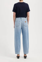 Light blue, wide-leg denim jeans with back pockets, styled with a short-sleeve navy top and open-toe black heels.
