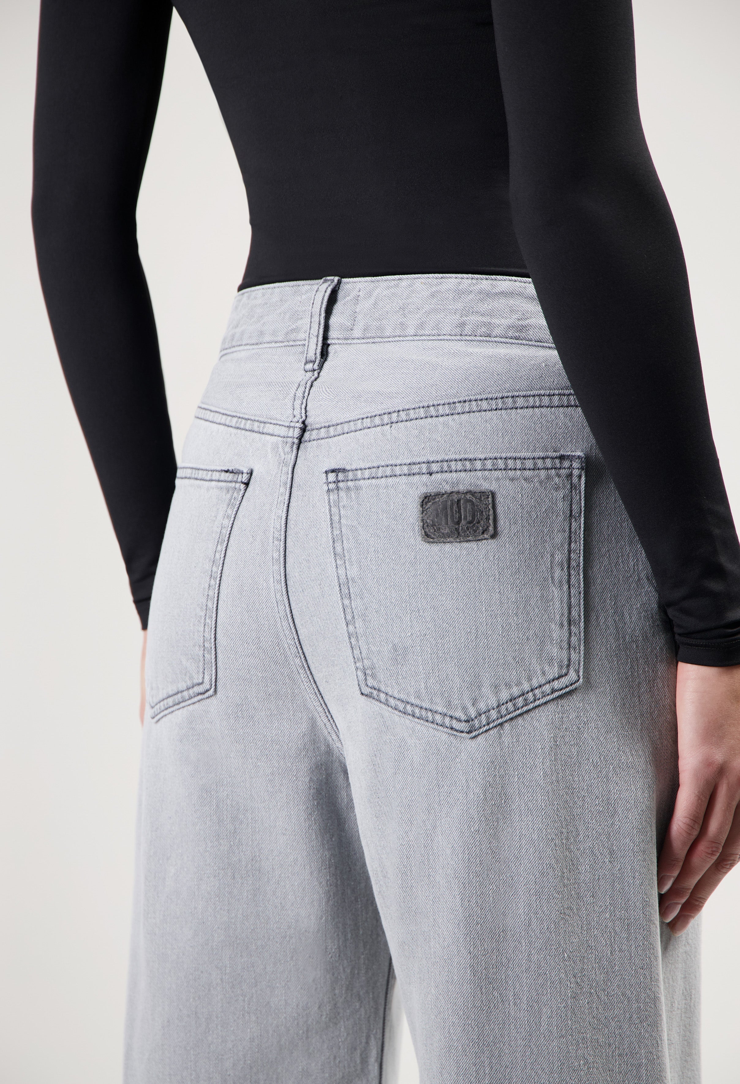 Light gray high-waisted denim jeans with wide-cut legs, paired with a fitted black long-sleeve top.