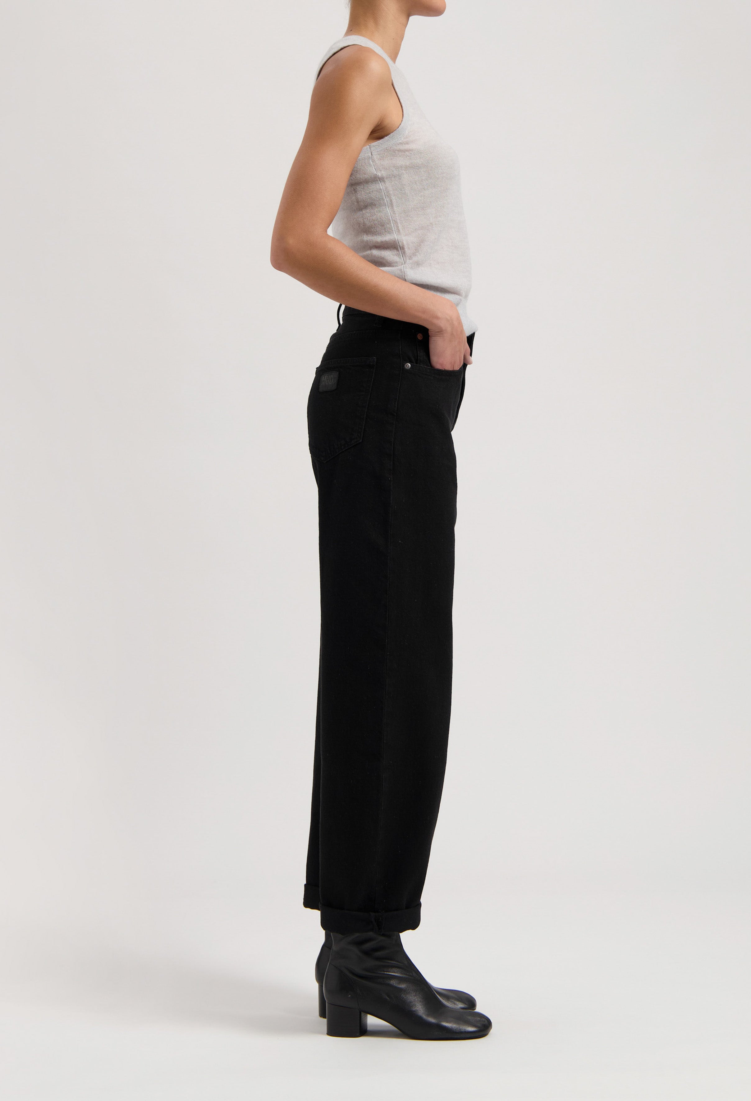 Classic black high-waisted jeans paired with a gray sleeveless top and black ankle boots, showcasing minimalist style.