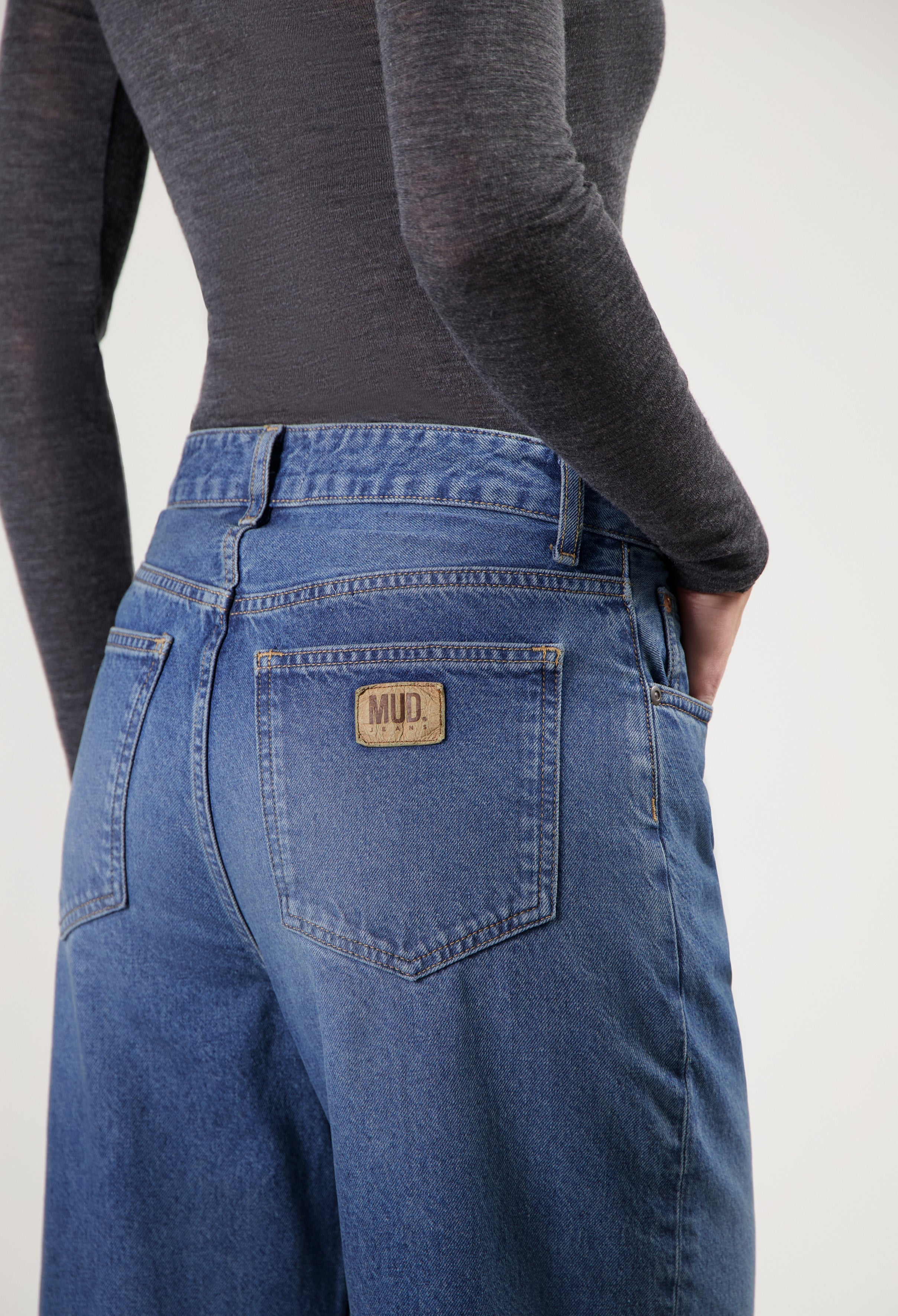 Dark blue, wide-leg MUD Jeans crafted from organic cotton, shown with a fitted charcoal gray long-sleeve top.
