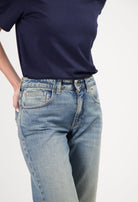 Model wearing classic light blue washed denim jeans with a navy blue short-sleeve top, hands in pockets.