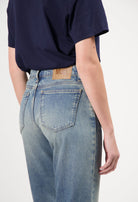 Person wearing light blue, eco-friendly MUD Jeans from organic cotton, displaying comfortable fit and stylish design.