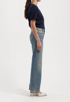 Women's classic blue denim jeans paired with a navy short-sleeve top and white pointed heels, side view.