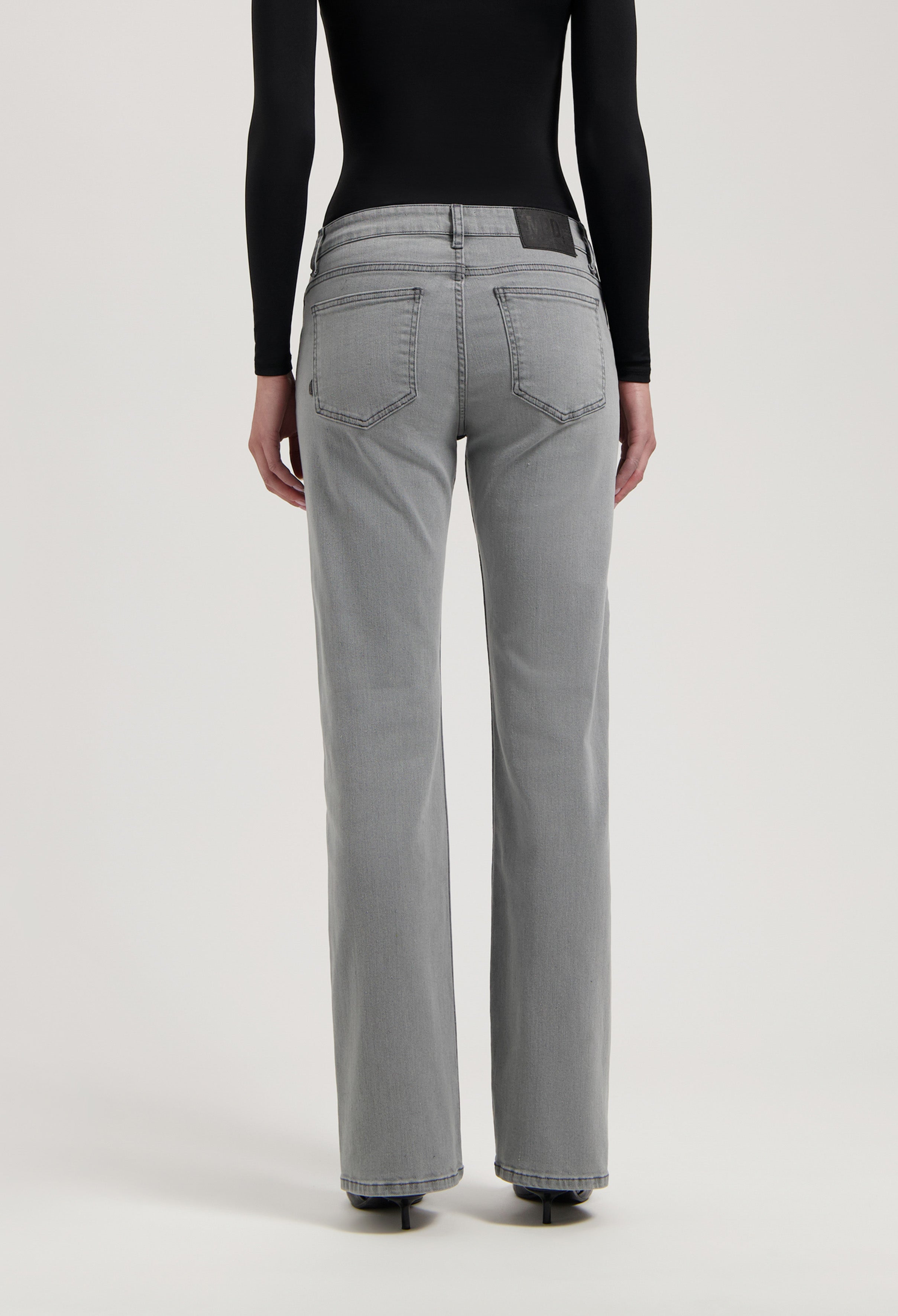 Gray high-waisted denim jeans with straight-leg fit, featuring detailed stitching and worn with a black long-sleeve top.