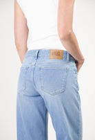 Light blue MUD Jeans made from organic cotton, featuring a high-waisted, wide-leg fit worn with a sleeveless white top.