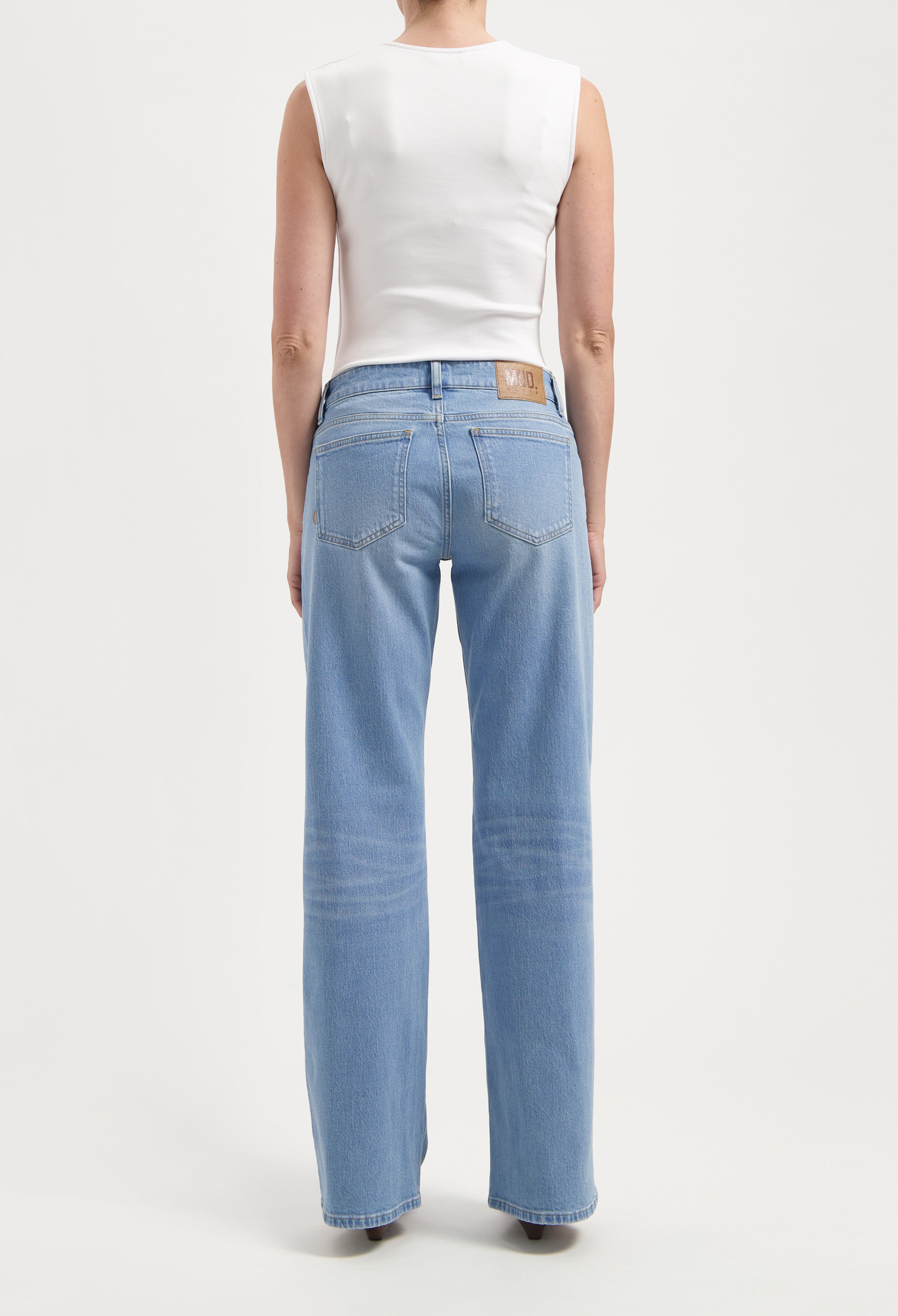 Back view of light blue, wide-leg jeans paired with a sleeveless white top, showcasing casual fit and sustainable material.