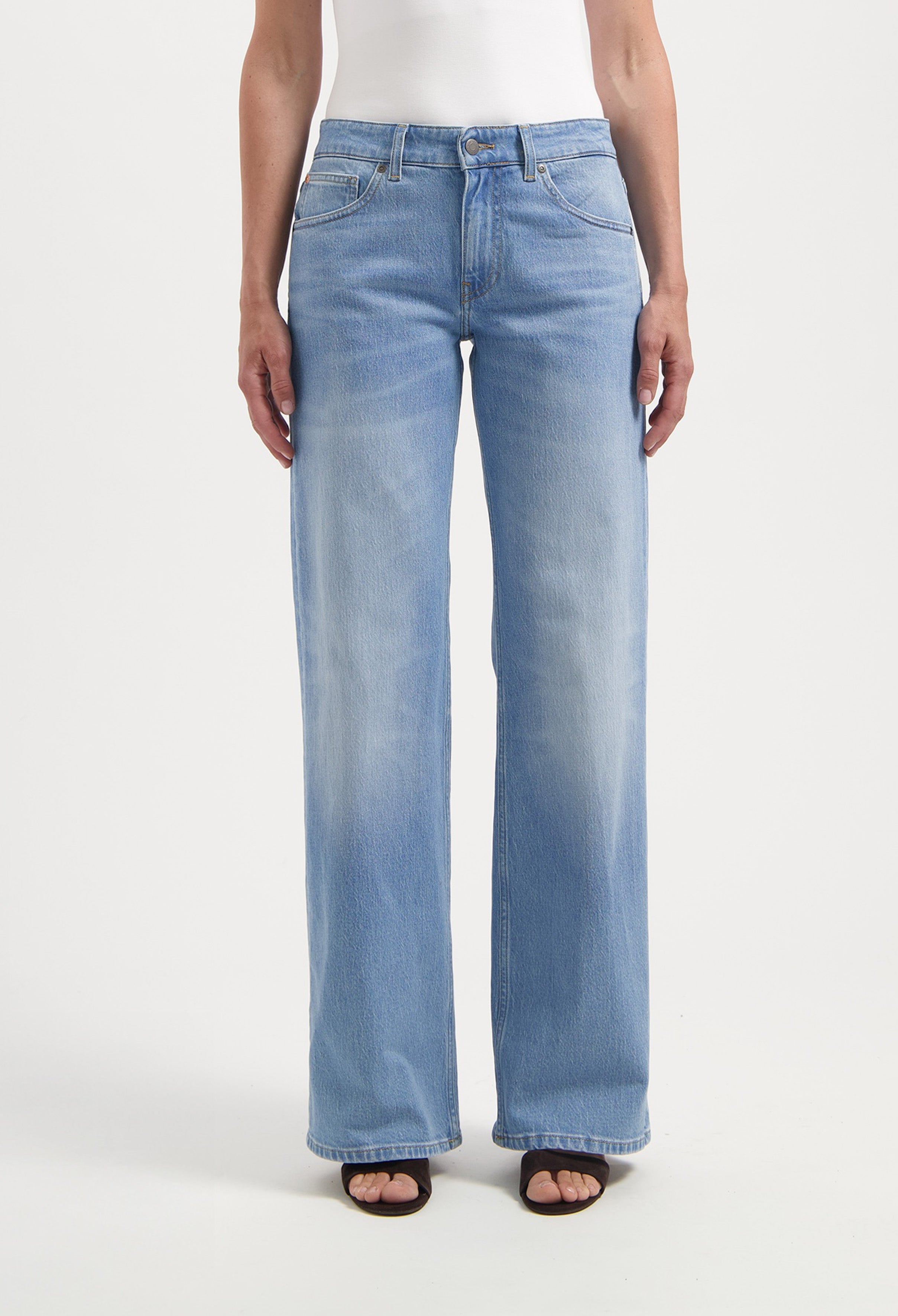 Wide-leg denim jeans in light blue, showcasing a casual fit, paired with a white tank top, creating a stylish casual look.