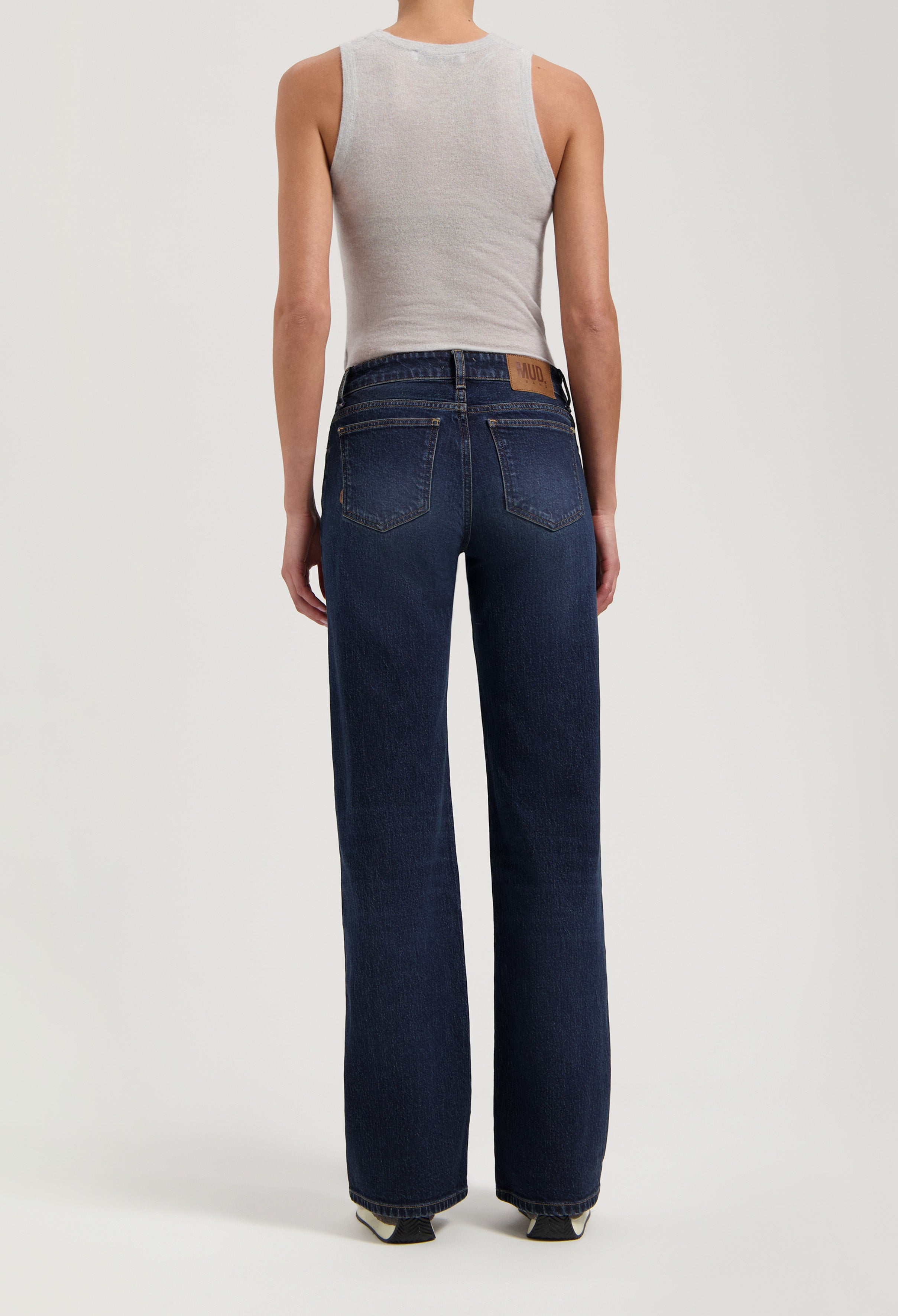 Person wearing dark blue wide-leg MUD Jeans crafted from sustainable organic cotton paired with a sleeveless gray top.