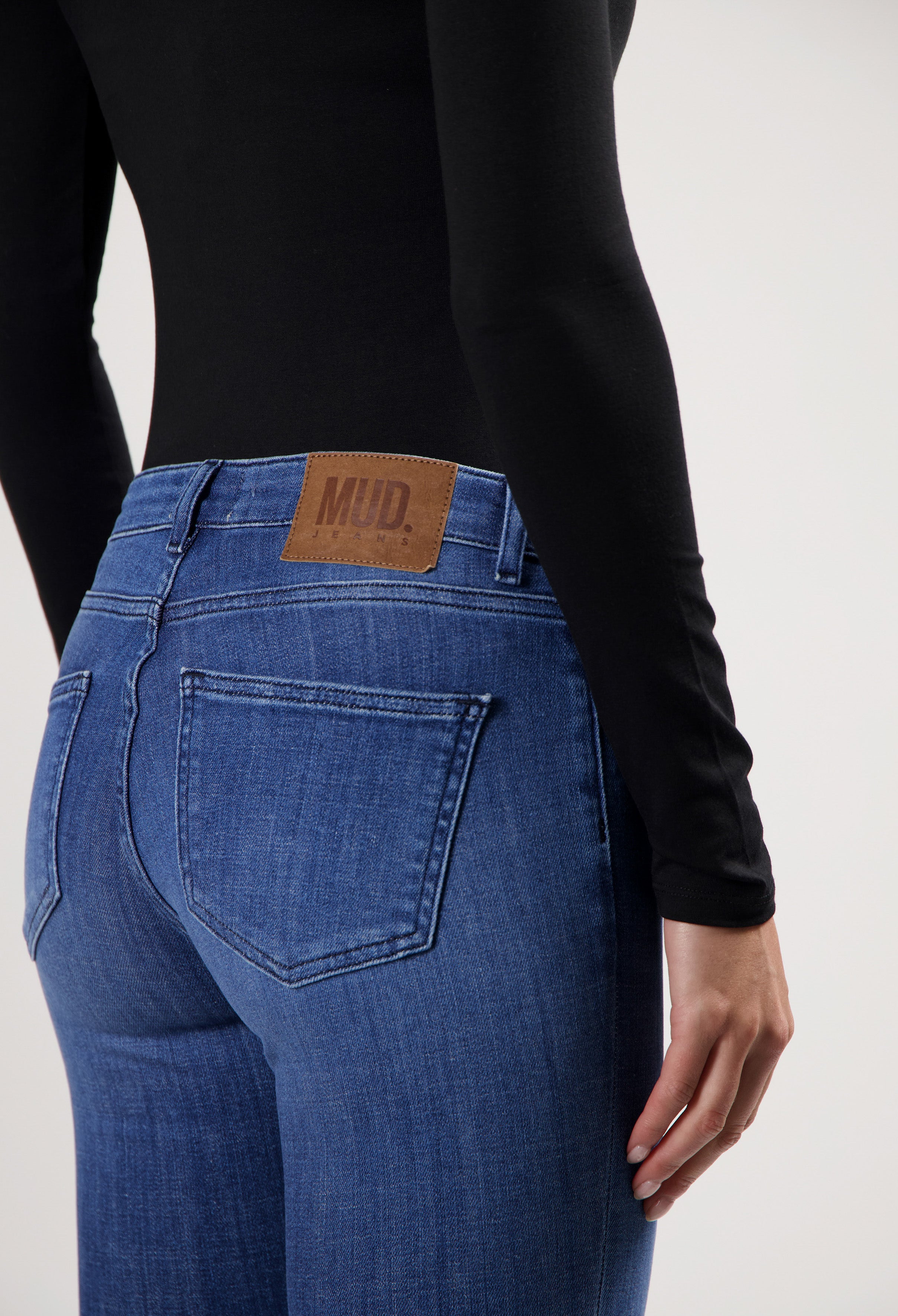 Slim-fit blue MUD Jeans crafted from sustainable cotton, shown with a black long-sleeve top, emphasizing eco-friendly fashion.