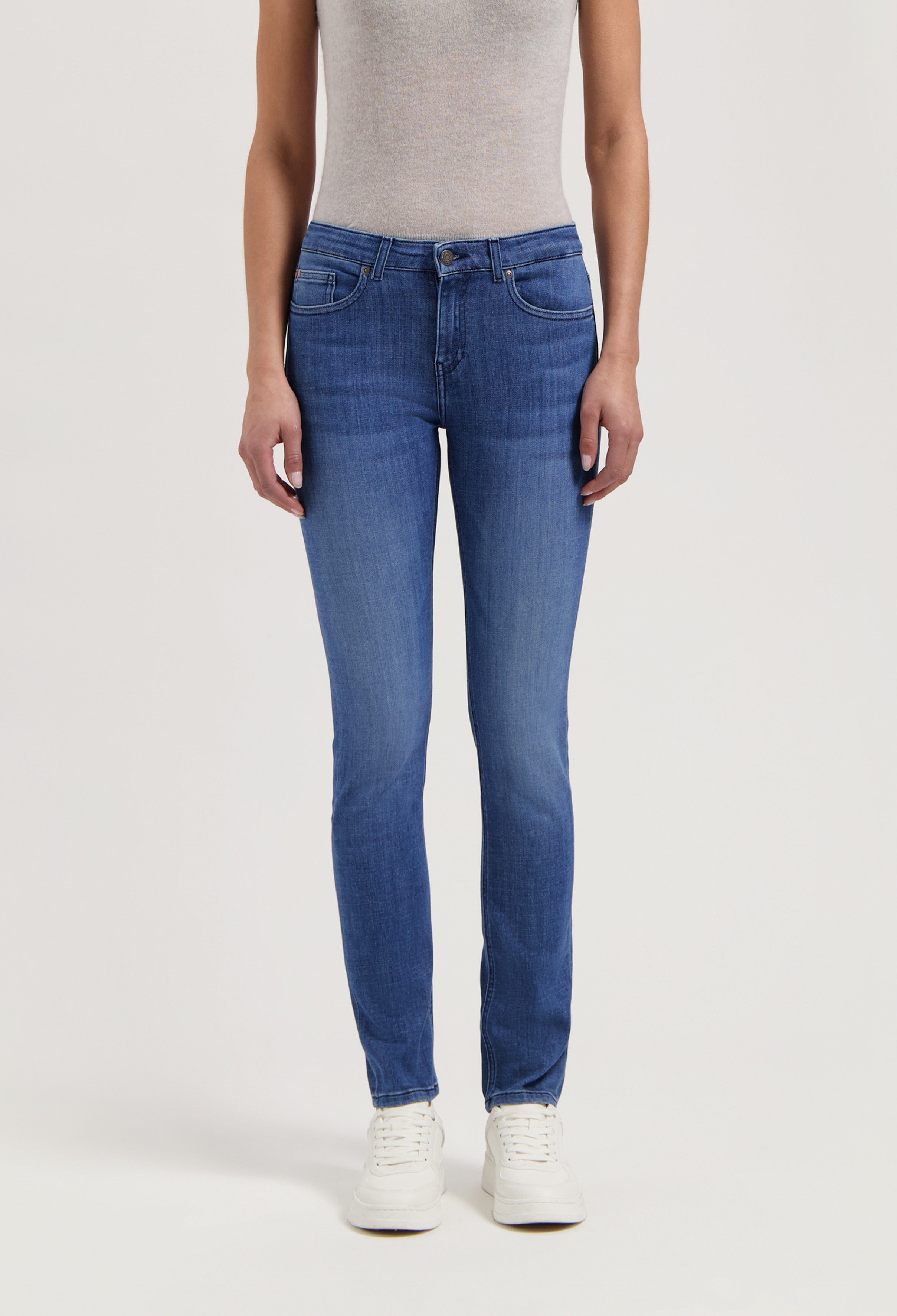 Blue slim-fit denim jeans paired with a light gray sleeveless top, completed with white sneakers, showcasing casual style.