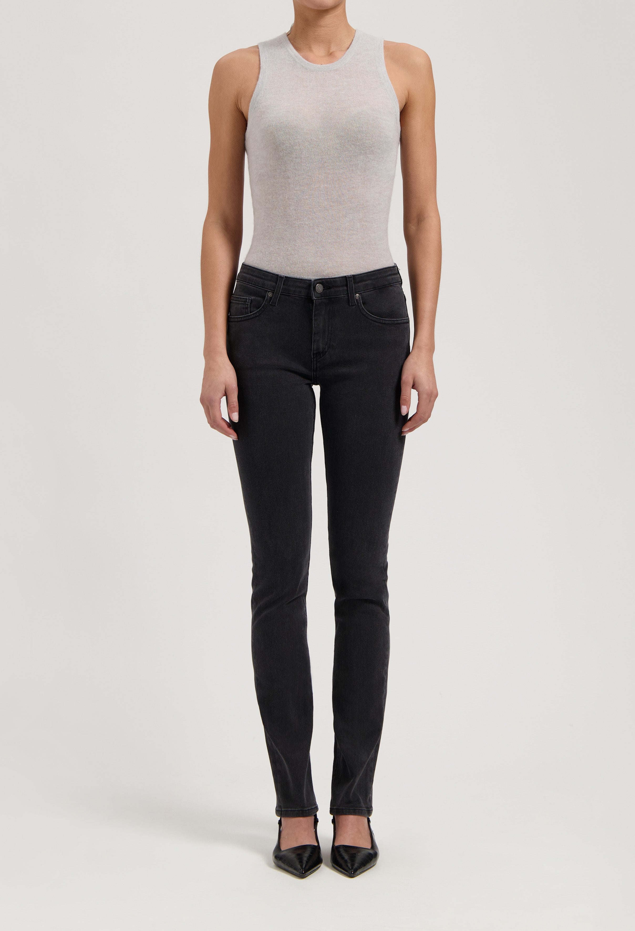 Sleeveless gray top paired with dark slim-fit jeans, showcasing a chic casual look with black pointed flats.