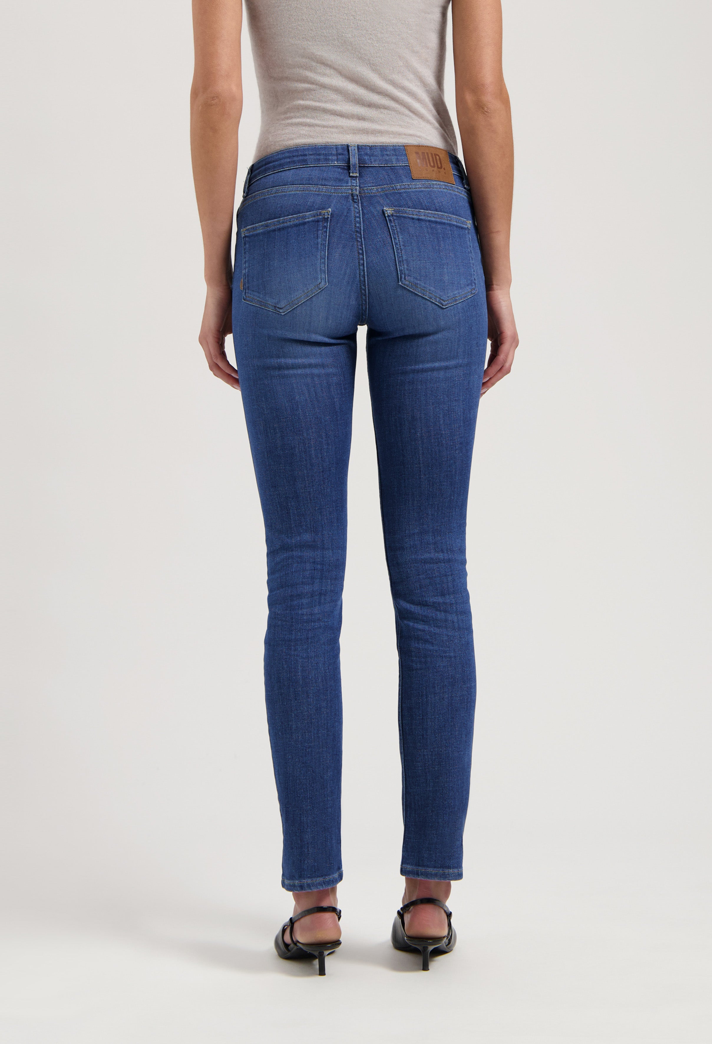 Back view of sustainable MUD Jeans made from organic cotton, showcasing slim-fit blue denim with classic stitching and branding.