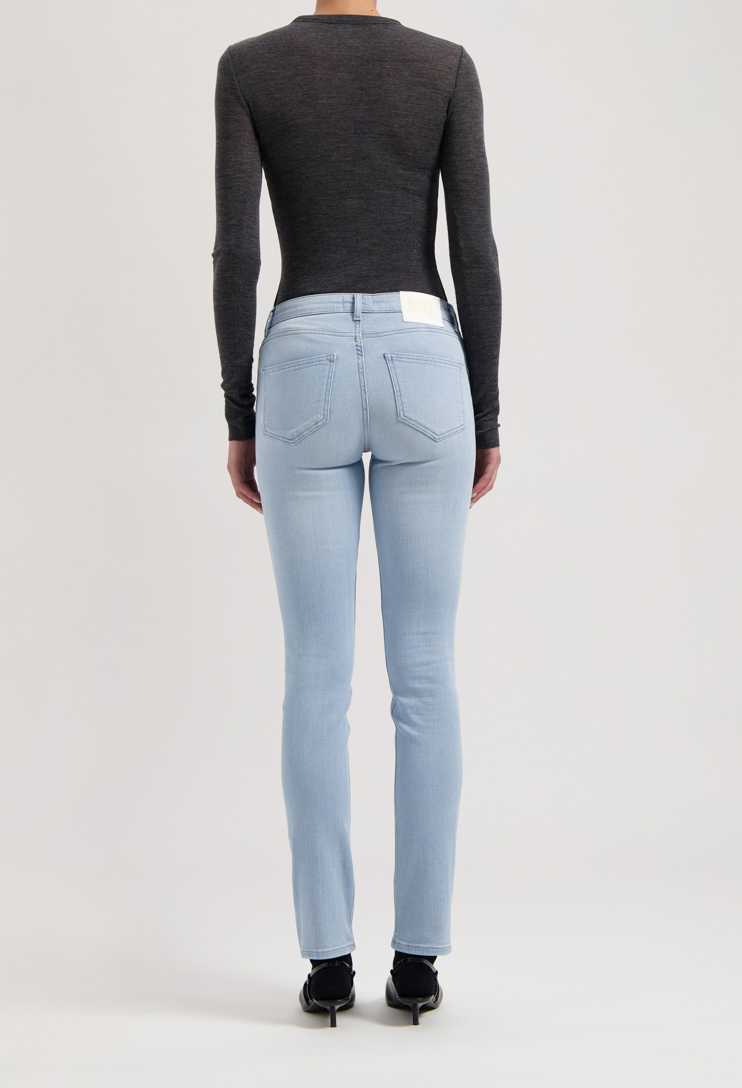 Dark gray, long-sleeve top paired with light blue, slim-fit MUD Jeans, displaying a sustainable fashion choice.