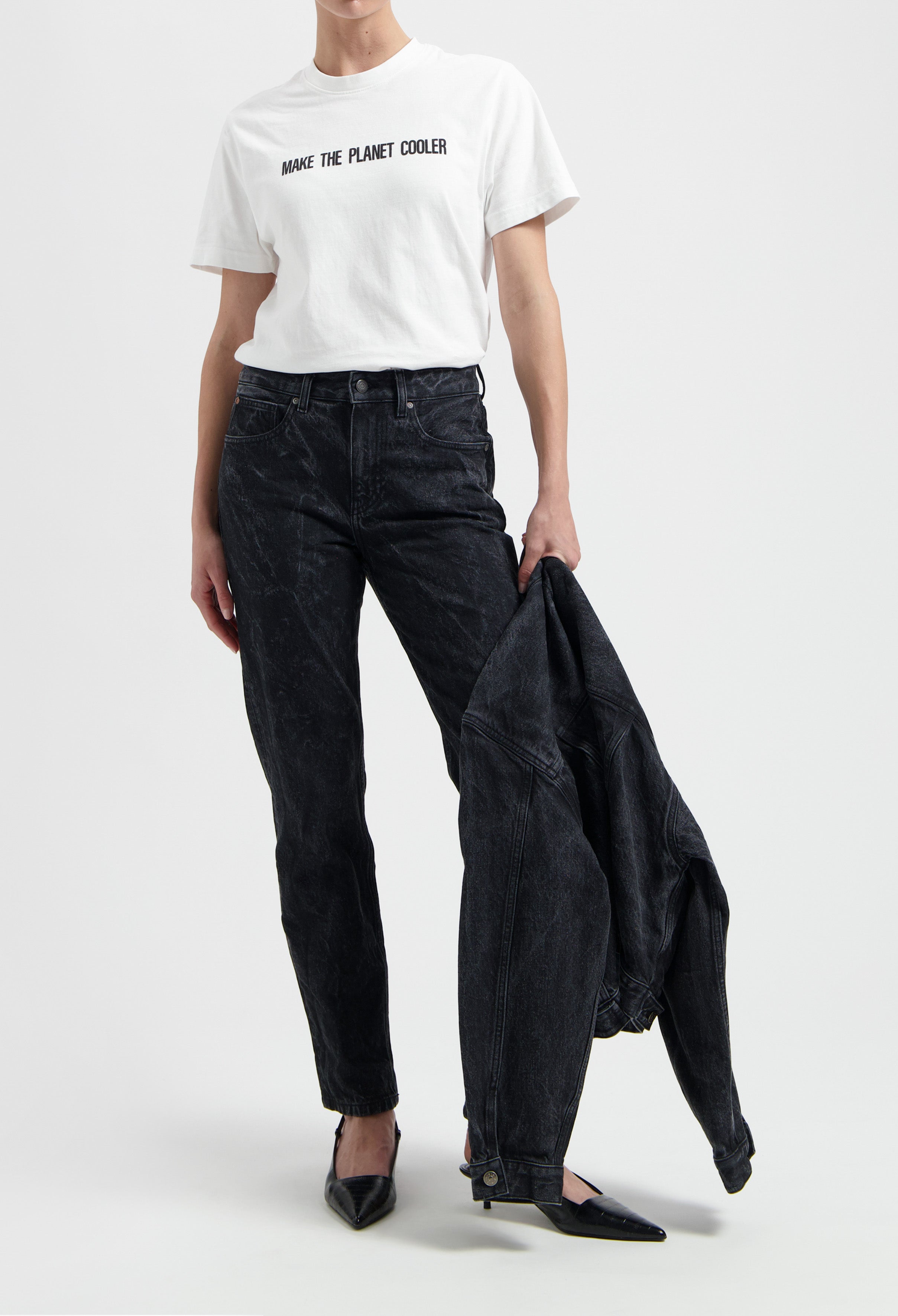 Casual outfit featuring a white slogan t-shirt and black acid wash jeans, styled with a denim jacket and black pointed shoes.