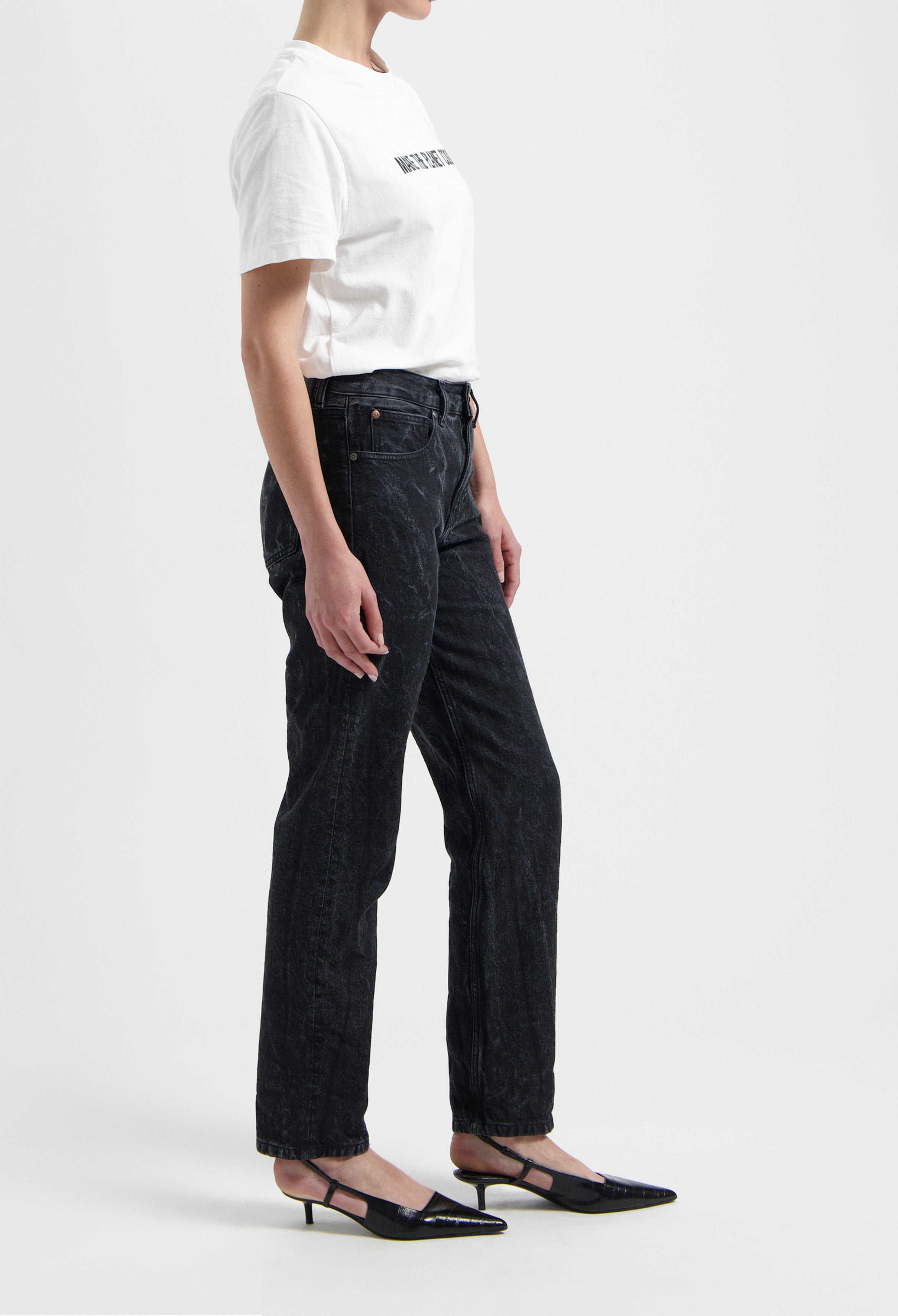 Casual white cotton t-shirt paired with loose-fit black jeans and pointed black heels, highlighting a trendy everyday outfit.