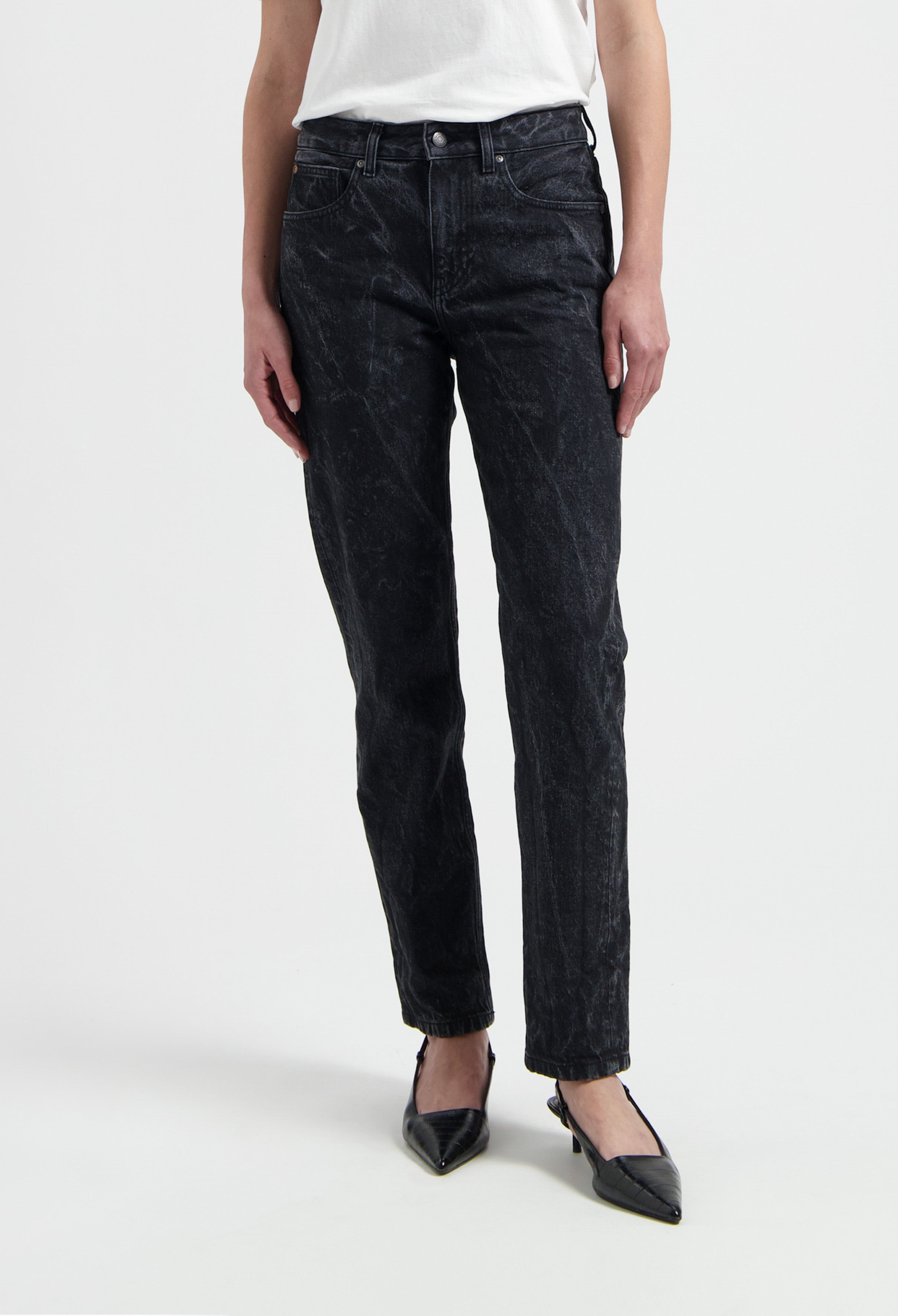 Stylish black denim jeans paired with a simple white t-shirt and black pointed heels, showcasing a casual chic look.
