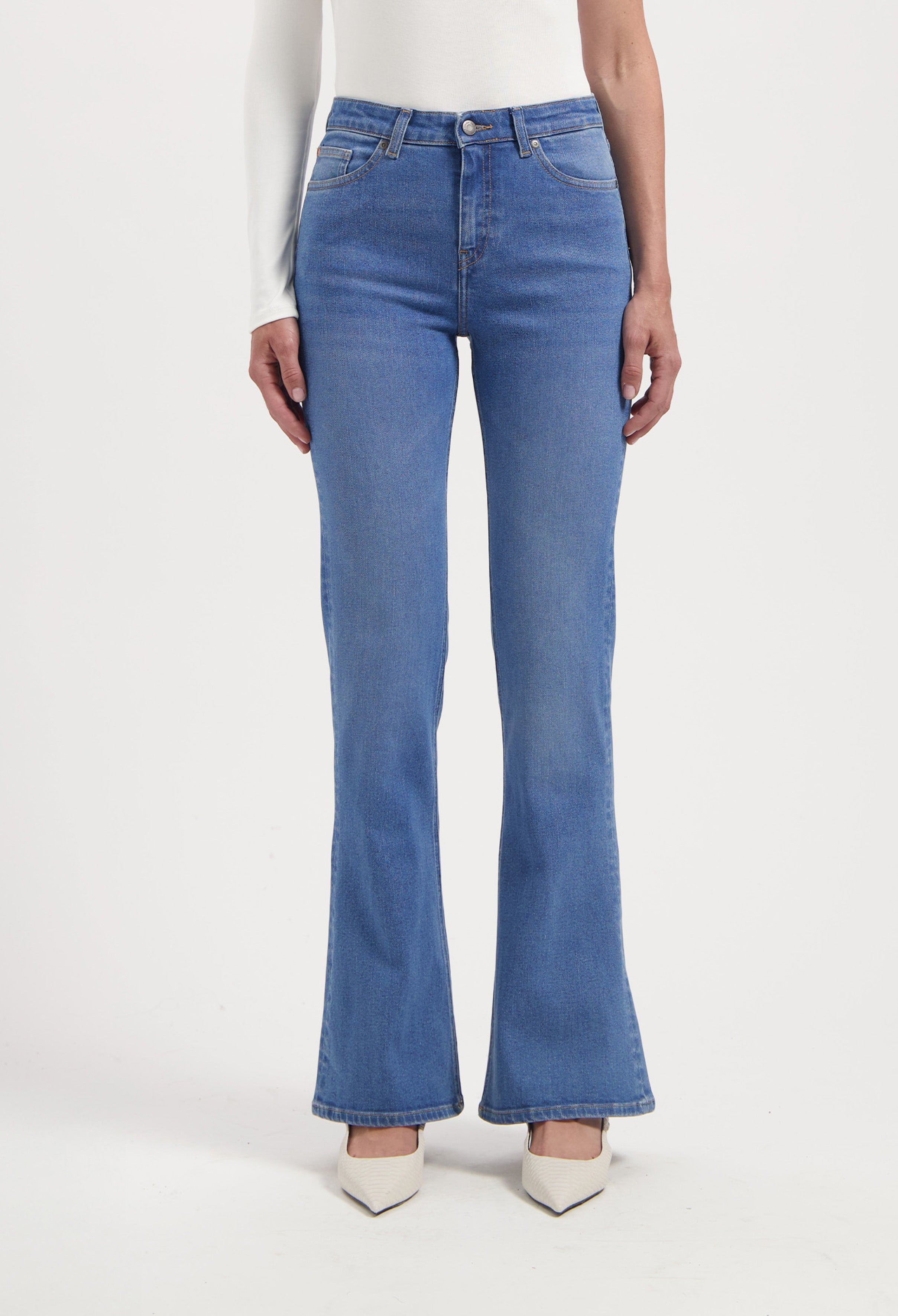 Women's blue high-waisted flared jeans paired with a white long-sleeve top, showcasing a classic, elegant style.