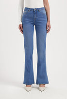 Women's blue high-waisted flared jeans paired with a white long-sleeve top, showcasing a classic, elegant style.