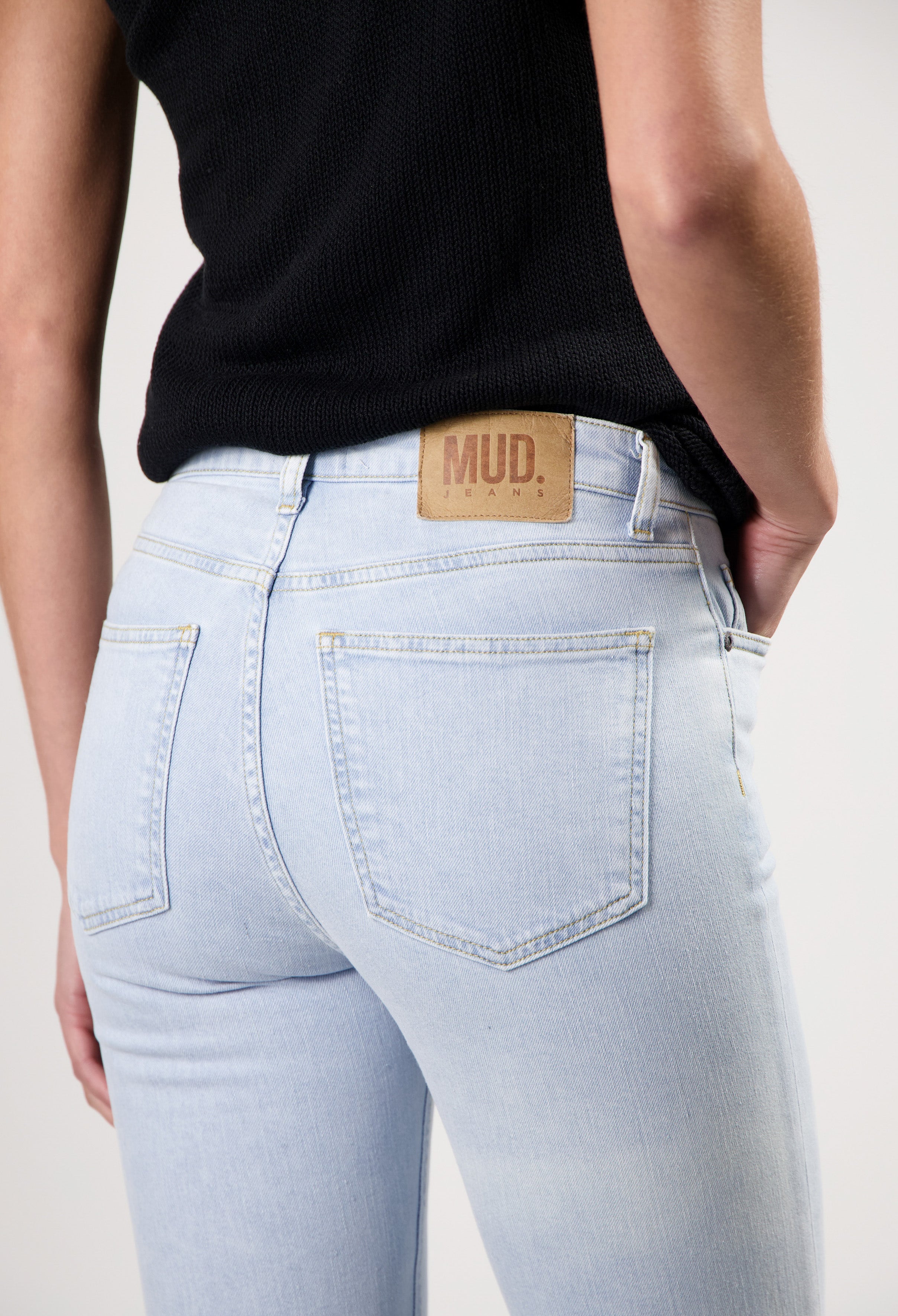 Light blue MUD Jeans made from organic cotton, showcasing the back view worn with a black textured top.