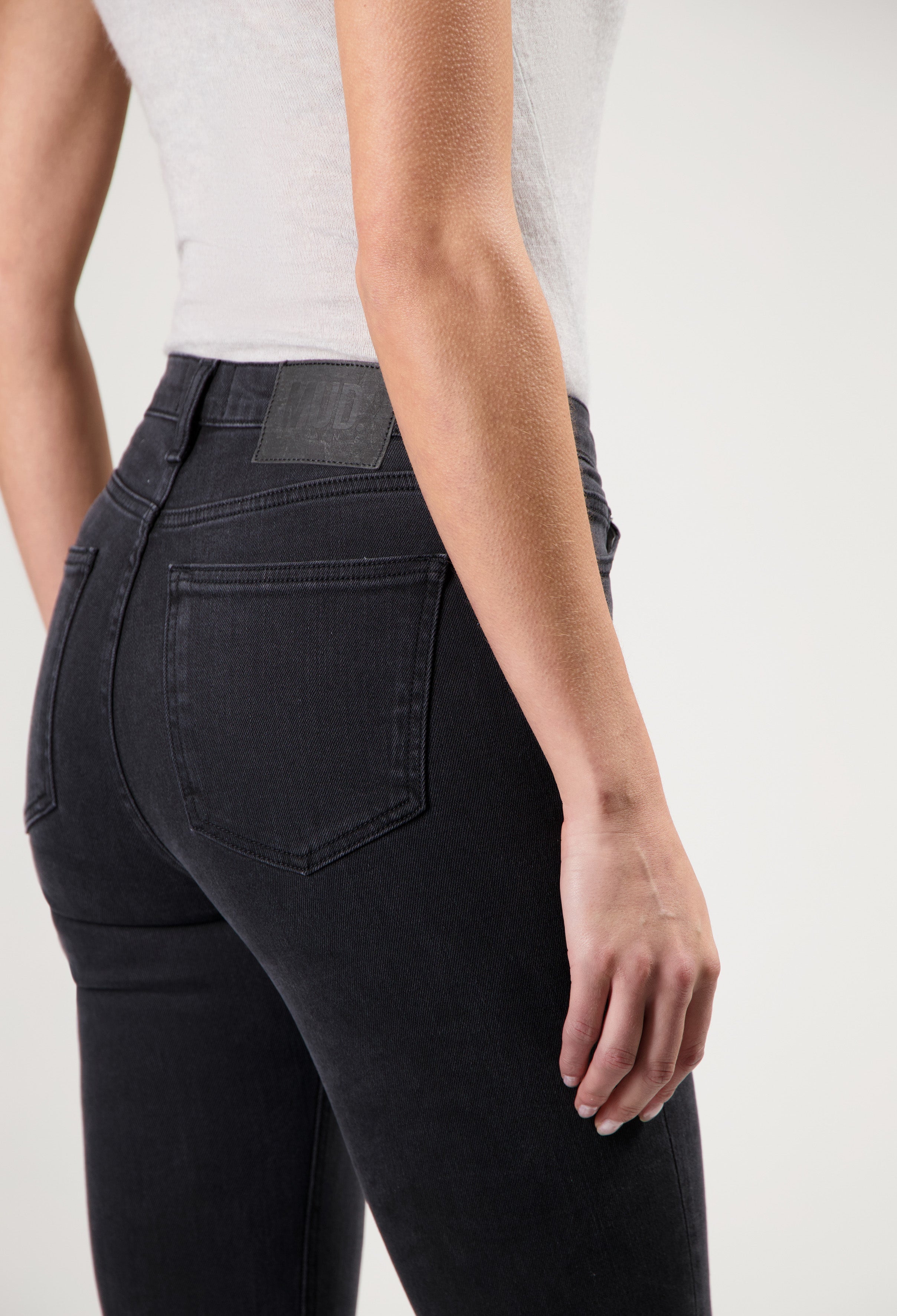 A person wearing sustainable black denim jeans from organic cotton paired with a fitted white sleeveless top.