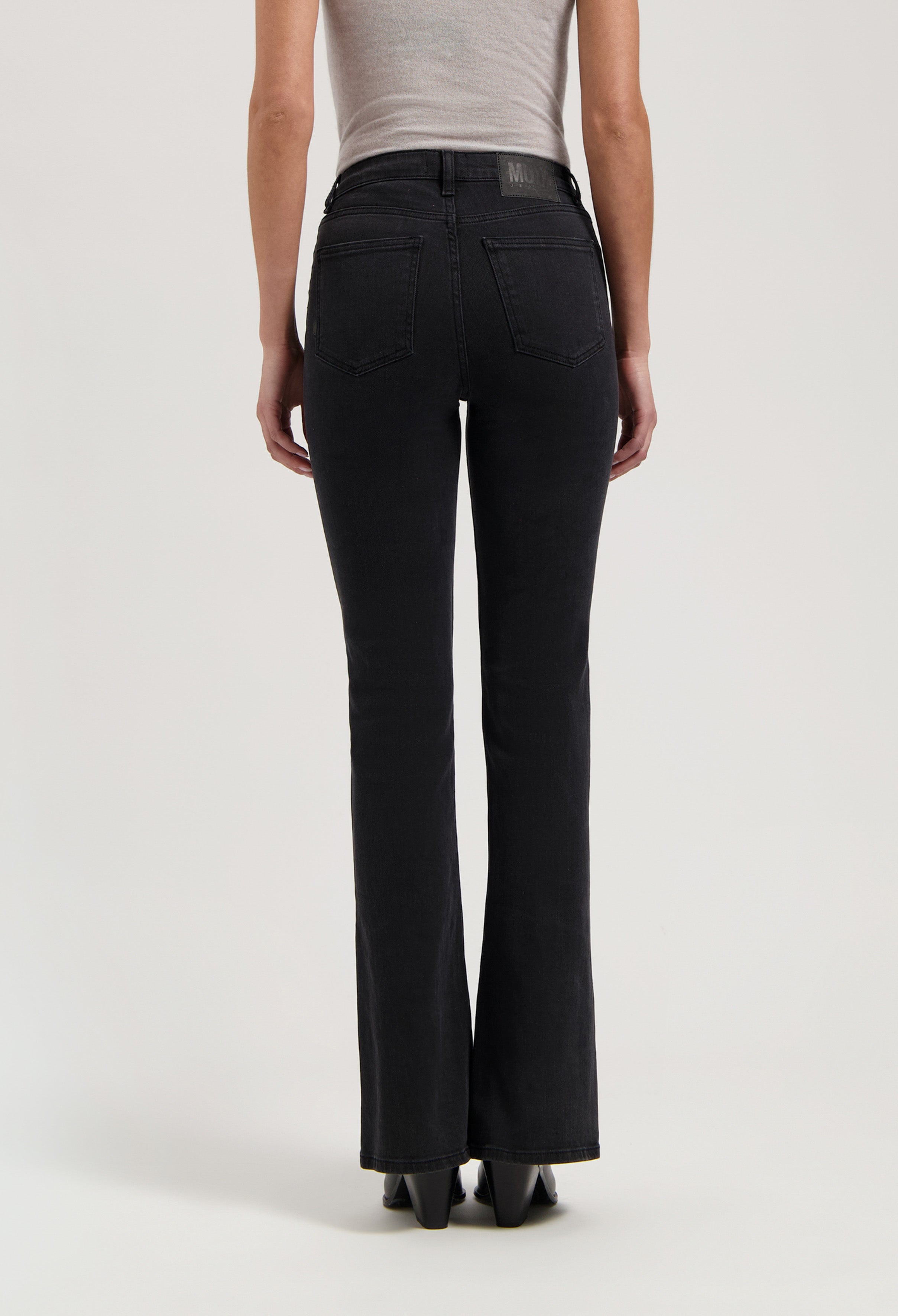Dark black, flared MUD Jeans in organic cotton, showcased from the back, paired with a light gray tank top.