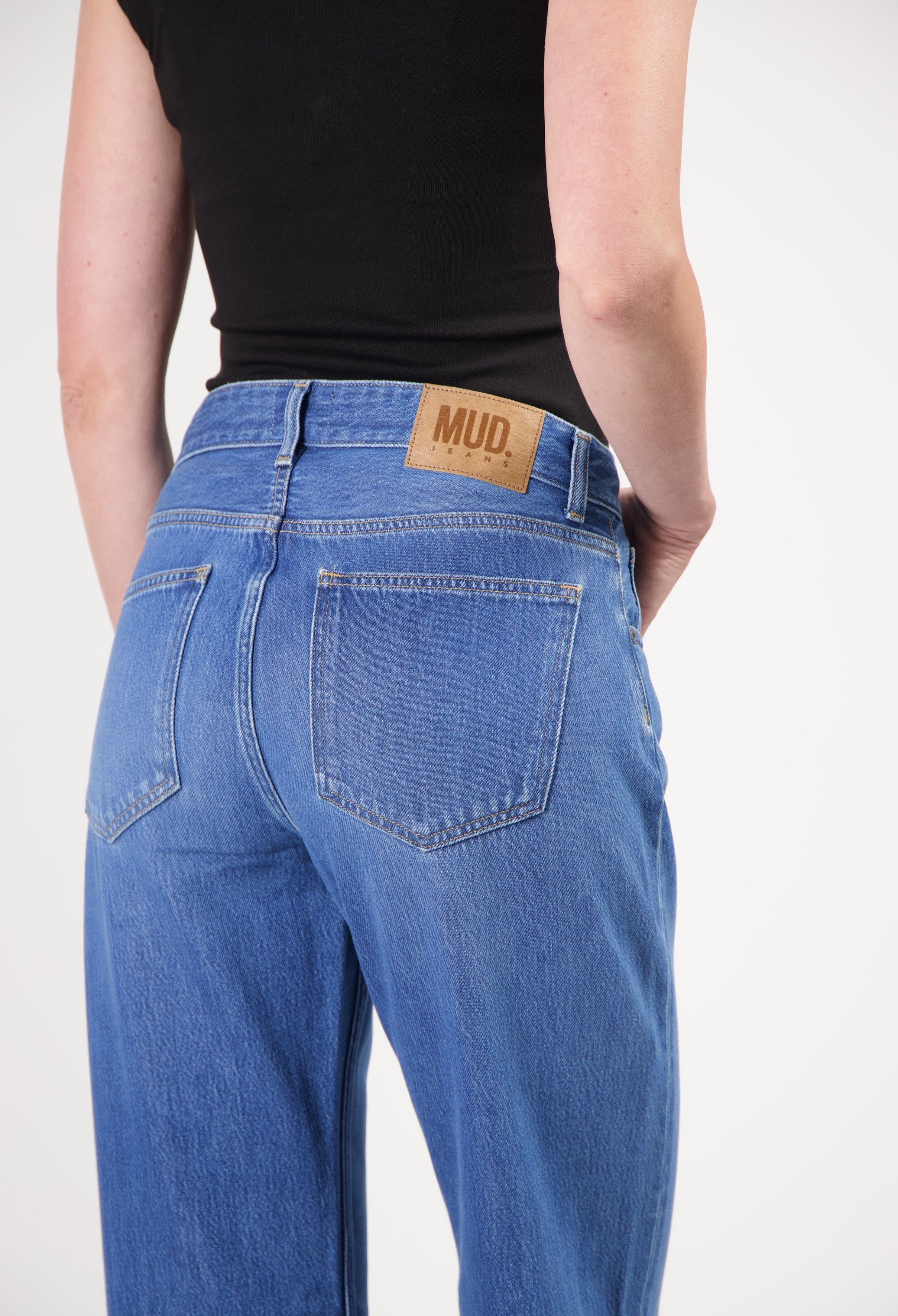 Back view of sustainable blue MUD Jeans made from organic cotton, showcasing classic cut and leather logo patch.