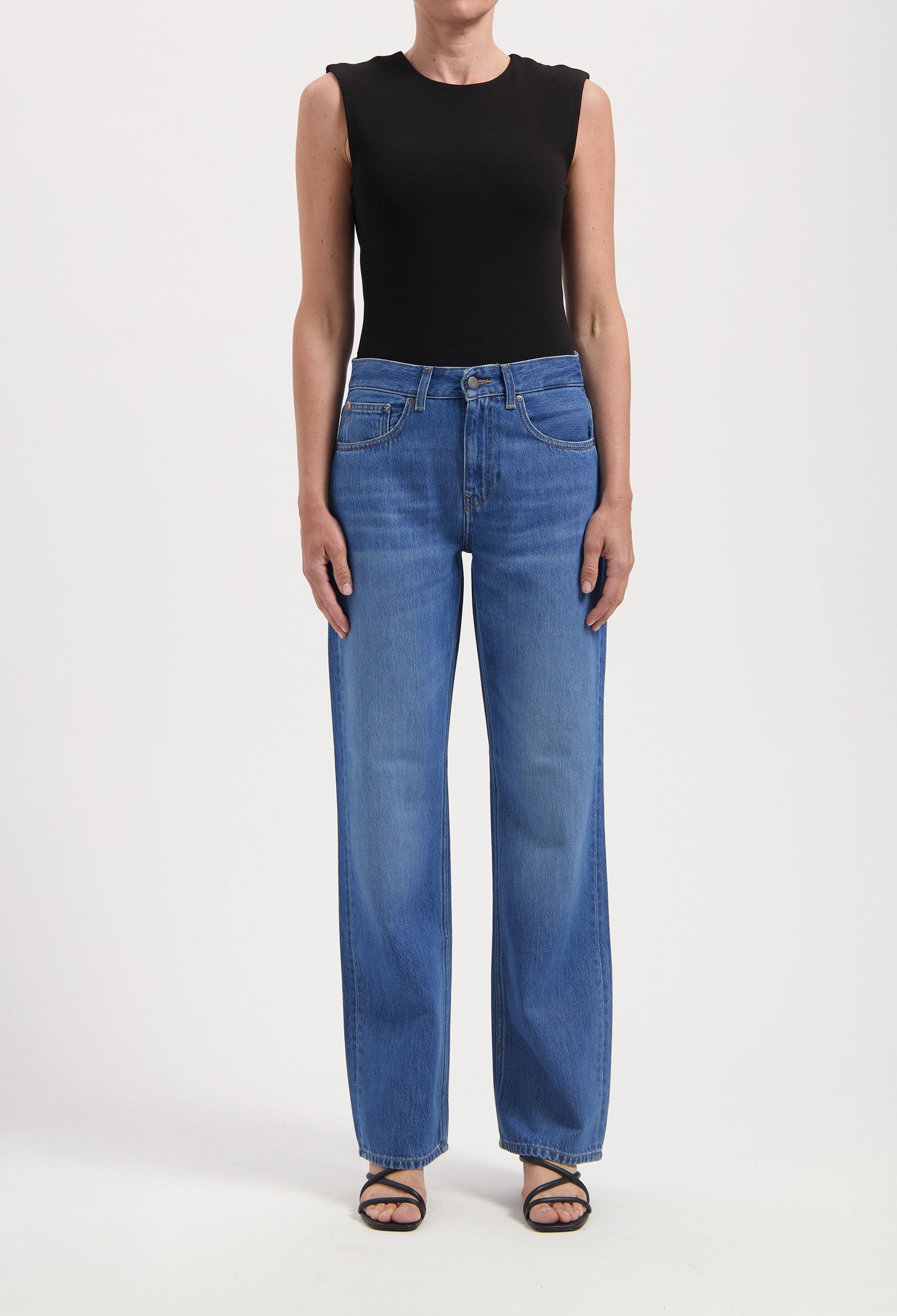 Wide-leg blue jeans paired with a sleeveless black top, demonstrating casual fashion with minimalist style.