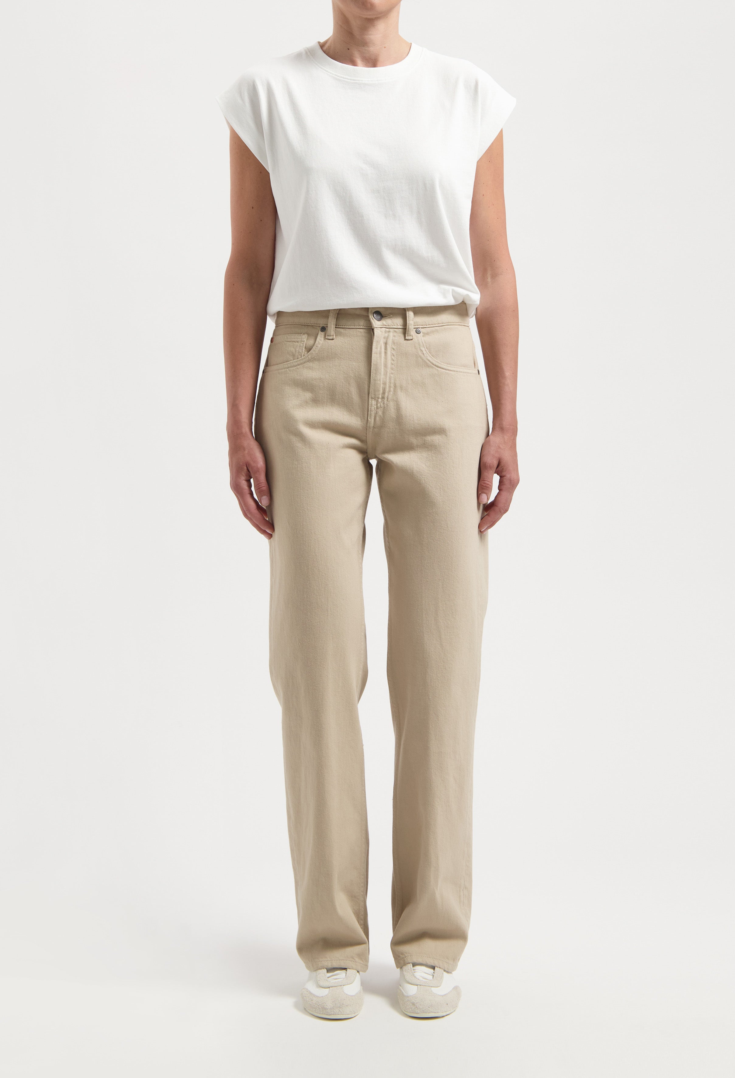 Casual beige straight-leg pants paired with a white short-sleeve top, highlighting relaxed fit and minimalist style.