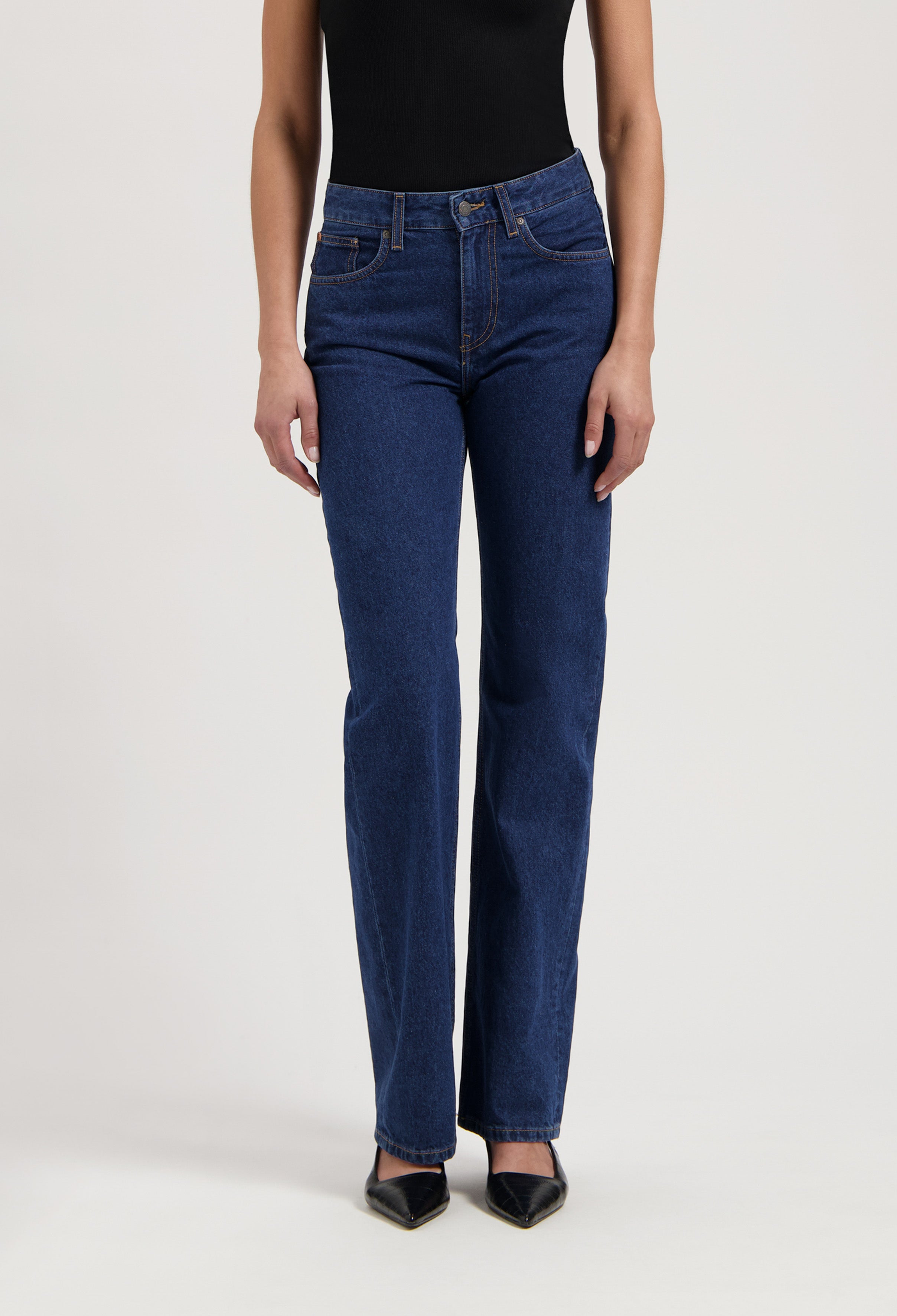 Dark indigo straight-leg jeans paired with a fitted black top, showcasing minimalist style and classic denim fit.