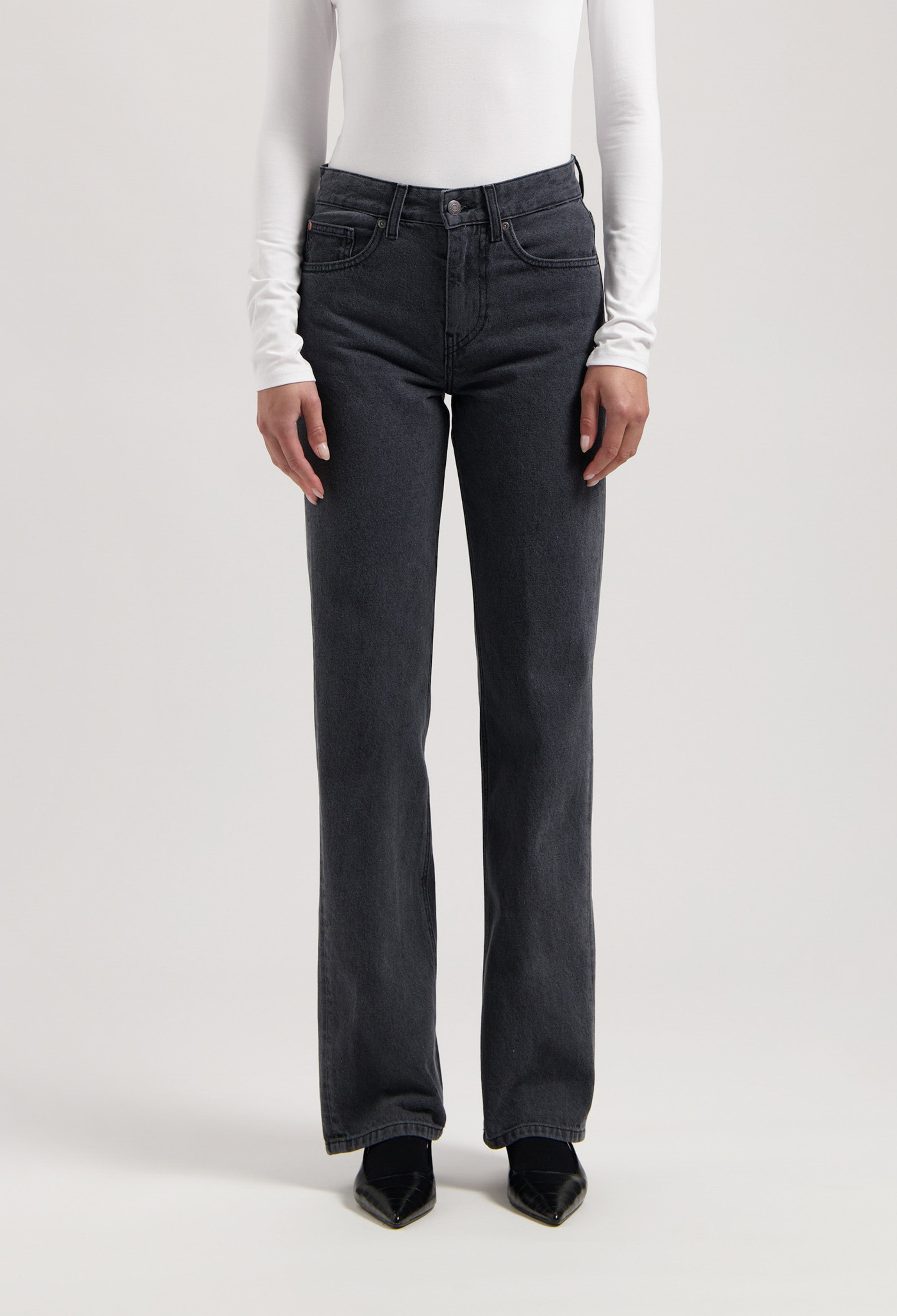 Straight-leg black denim jeans paired with a fitted white long-sleeve top, showcasing a minimalist style.