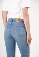 Person wearing sustainable MUD Jeans in a light blue wash, showcasing a back view with a white short-sleeve top.