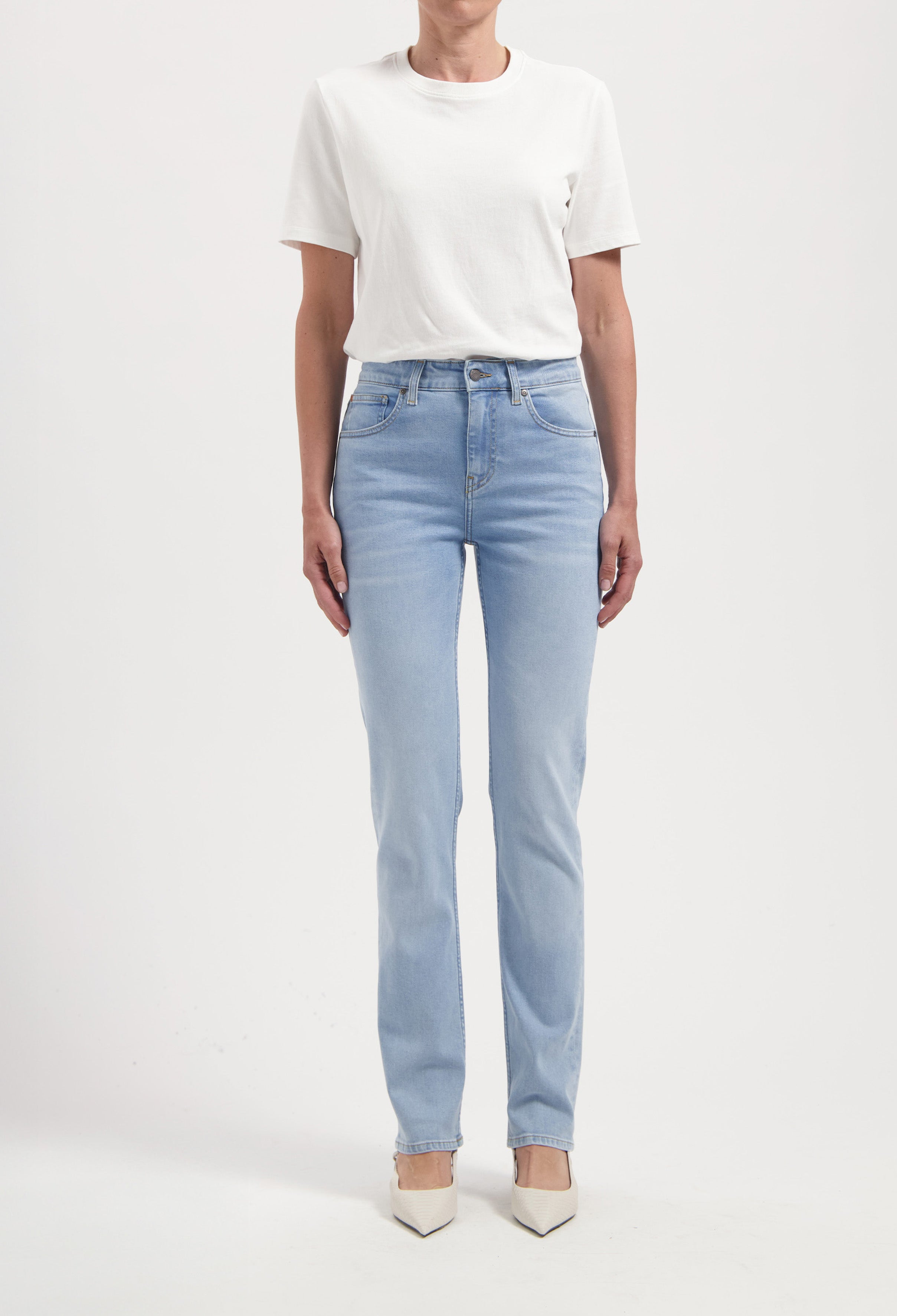 A pair of light blue straight-leg jeans paired with a simple white t-shirt, highlighting a casual fashion style.