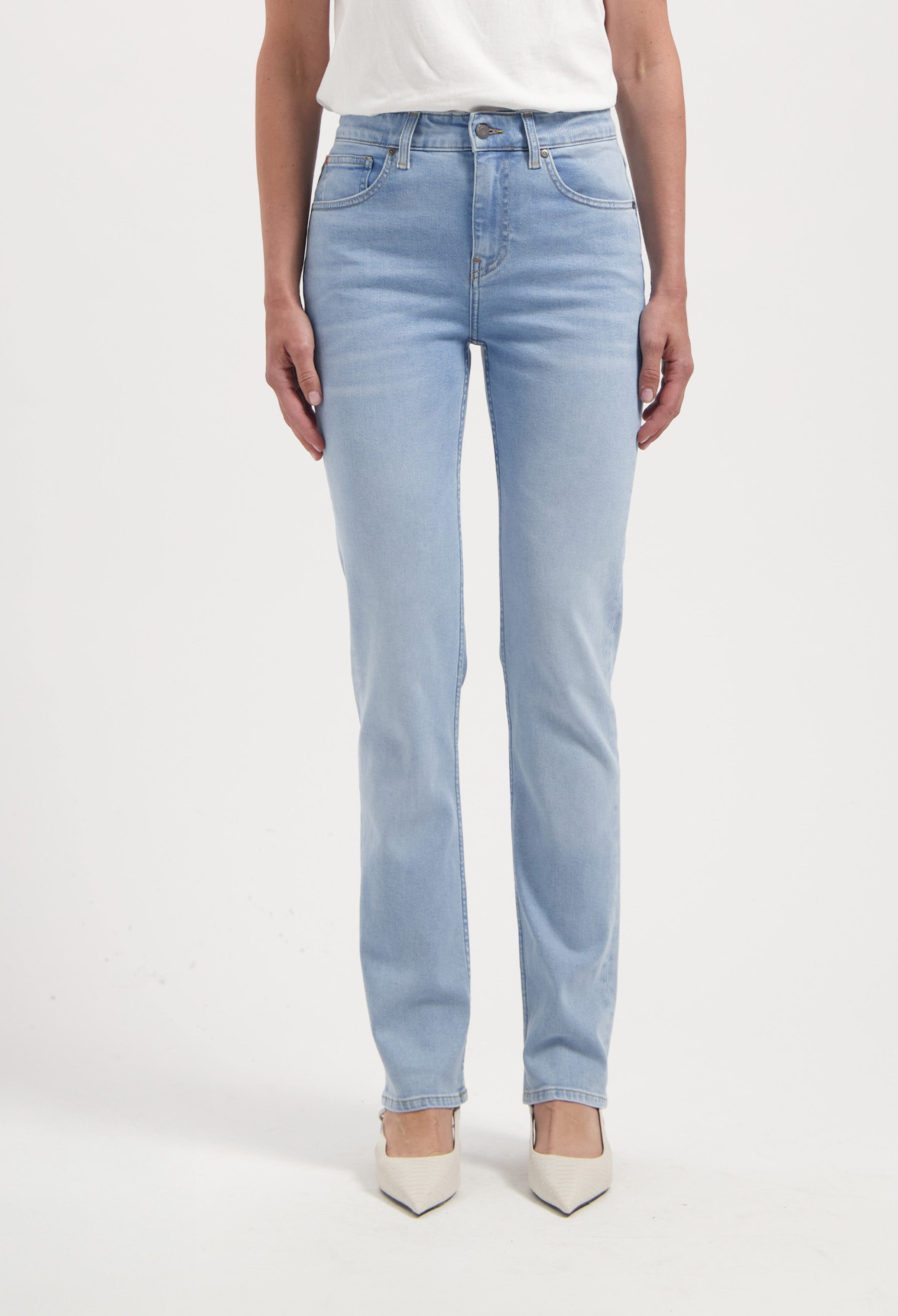 Light blue straight-cut denim jeans made from cotton, paired with an off-white top and white pointed-toe shoes.