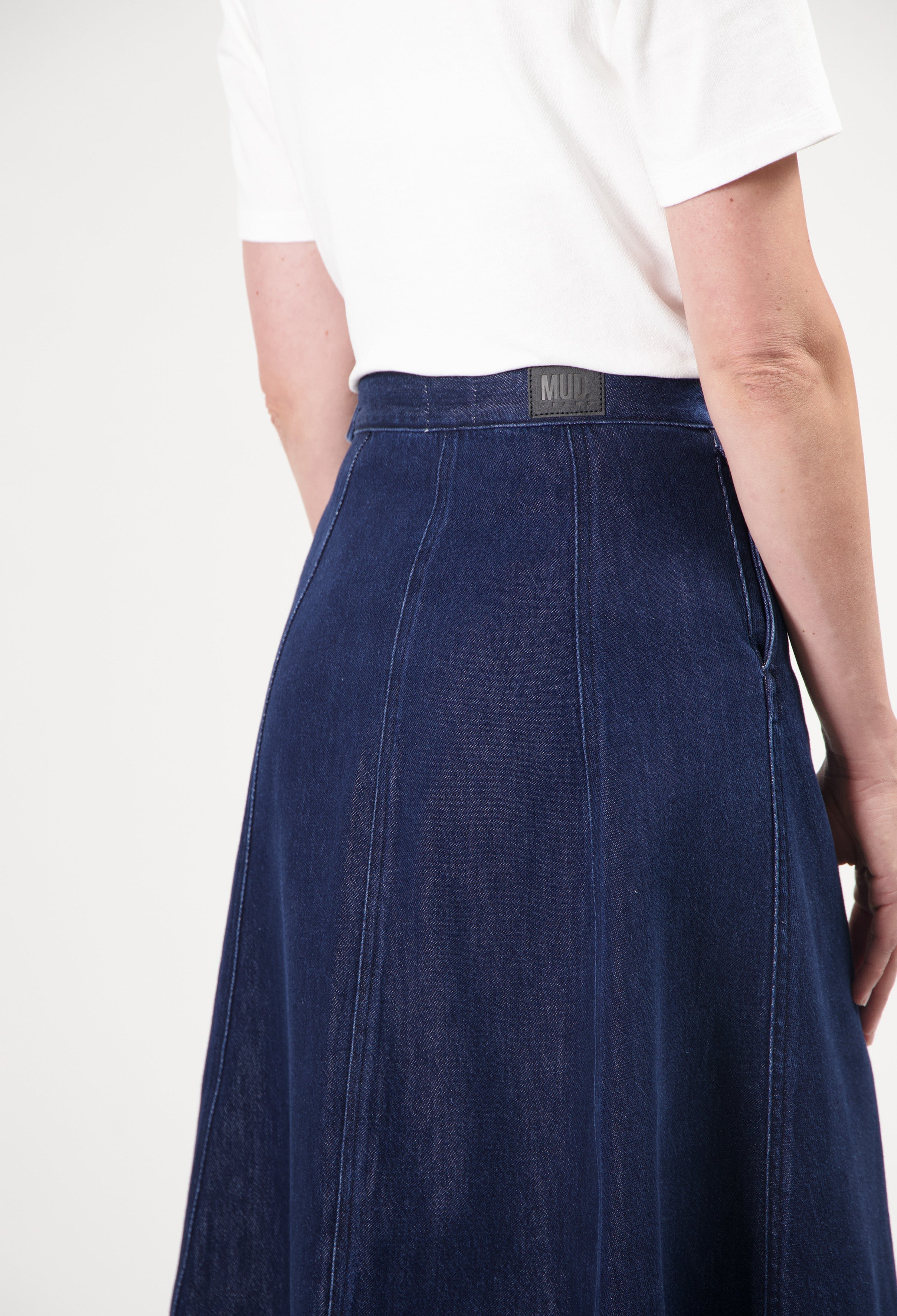 High-waisted dark blue MUD Jeans skirt made from organic cotton, paired with a classic white short-sleeve top.