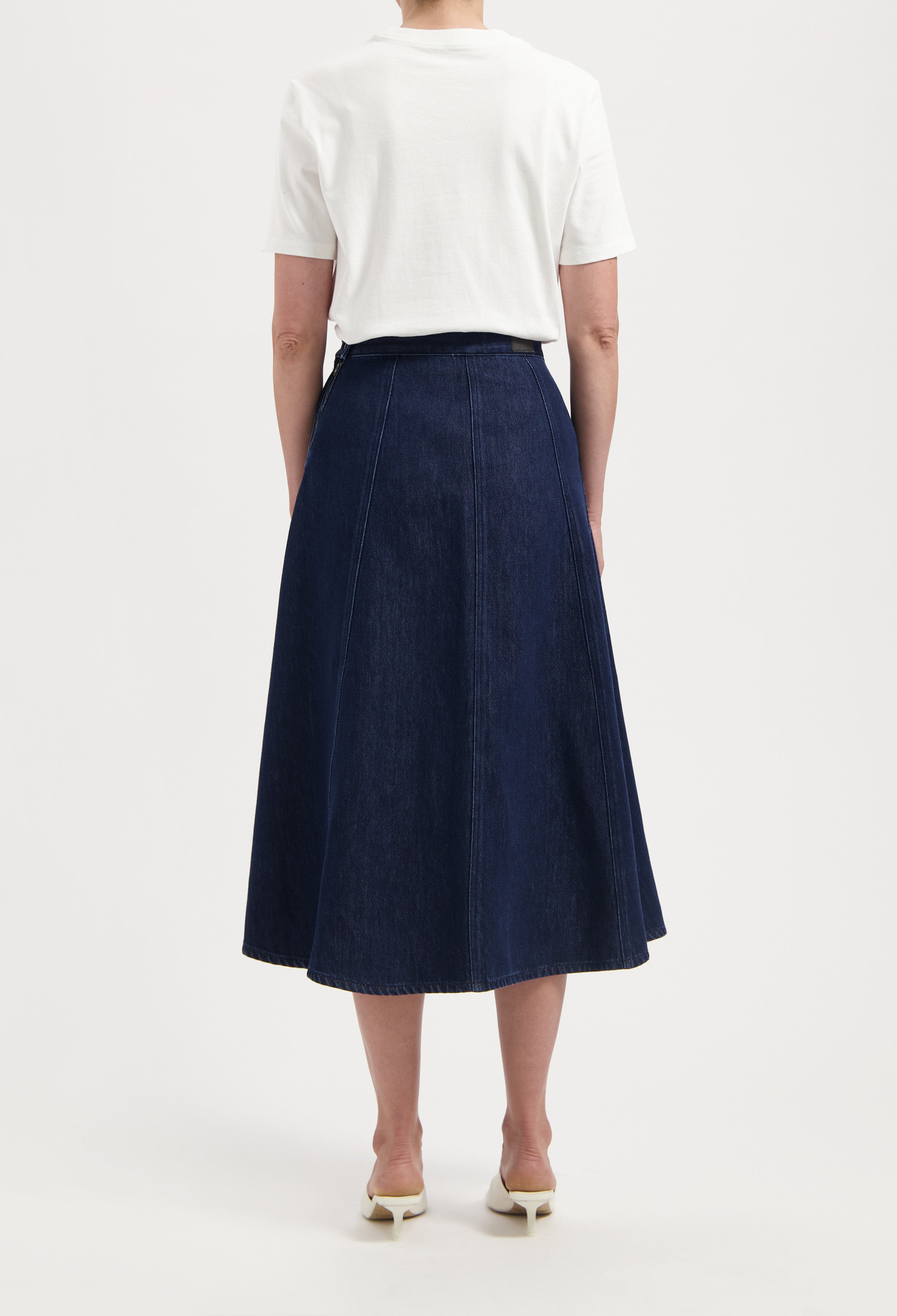 A-line dark blue denim skirt paired with a white short-sleeve top, showcasing a casual, elegant look from the back.