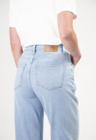 Light blue MUD Jeans crafted from organic cotton, featuring a relaxed fit and subtle stitching, paired with a white T-shirt.