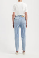 Back view of a person wearing light blue, straight-leg jeans paired with a white short-sleeve top, showcasing casual style.