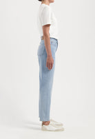 A pair of high-waisted light blue denim jeans paired with a plain white short-sleeve top, showcasing a side view.