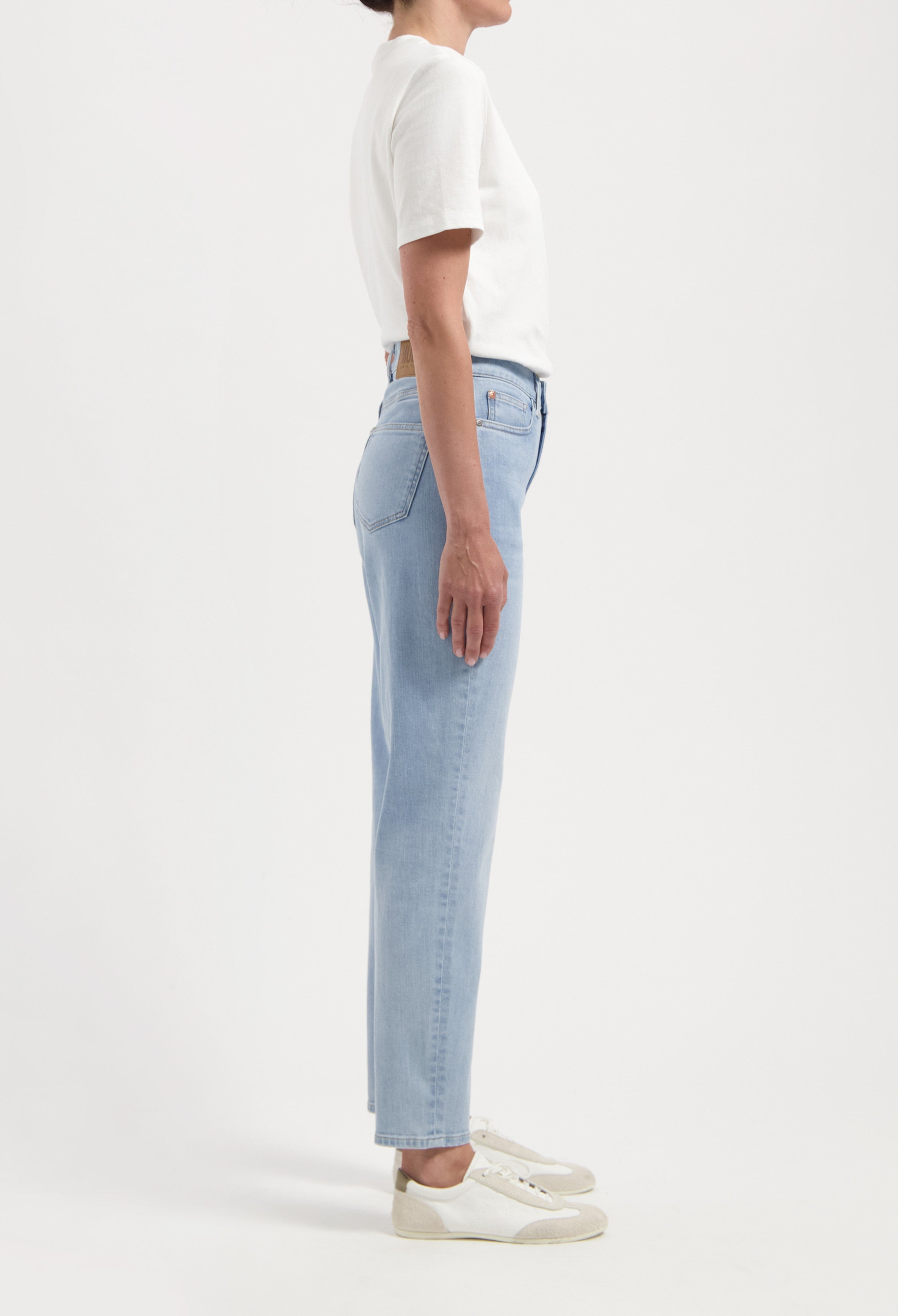 A pair of high-waisted light blue denim jeans paired with a plain white short-sleeve top, showcasing a side view.