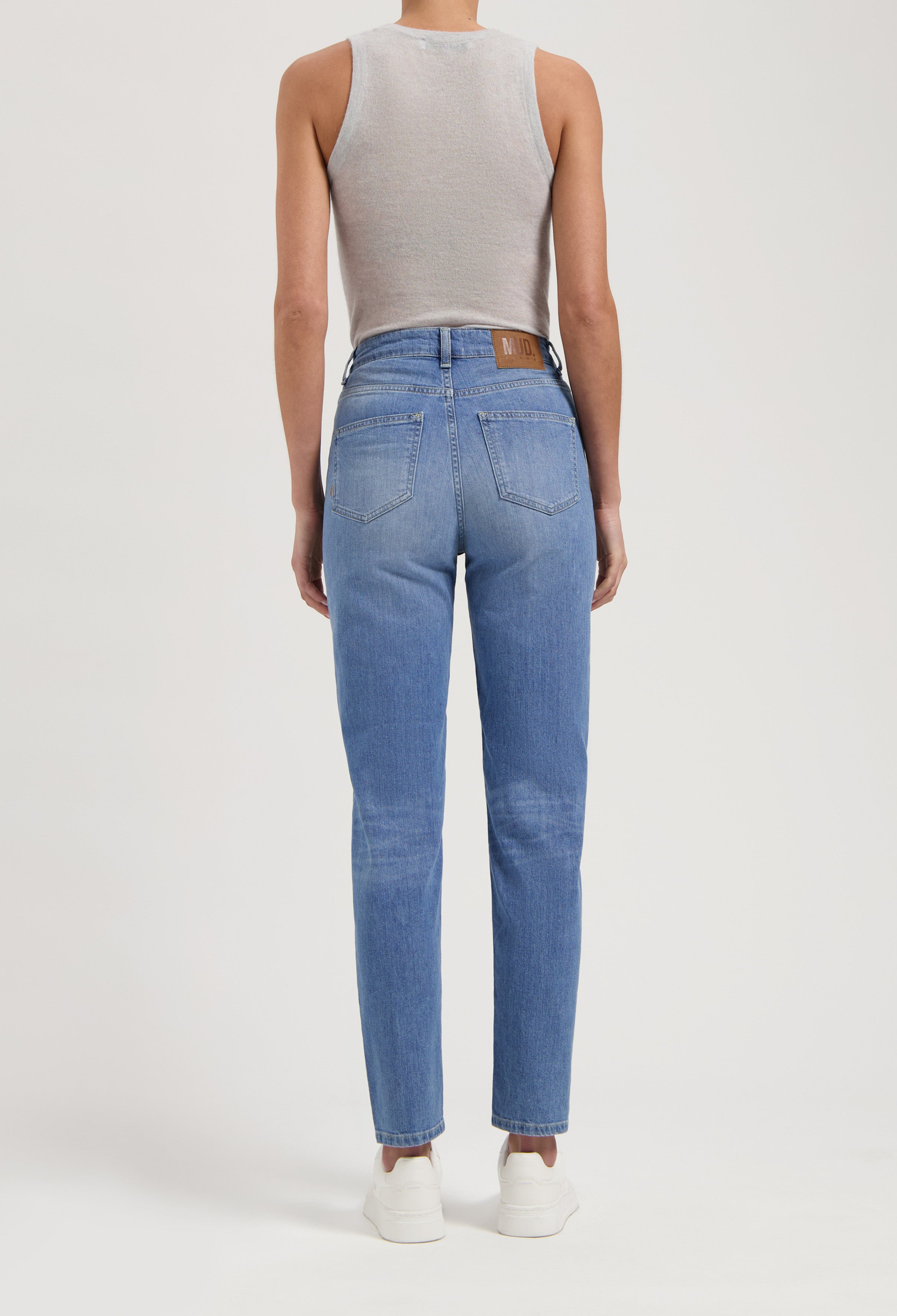 Back view of slim-fit blue denim jeans paired with a sleeveless gray top, showcasing a casual and timeless style.