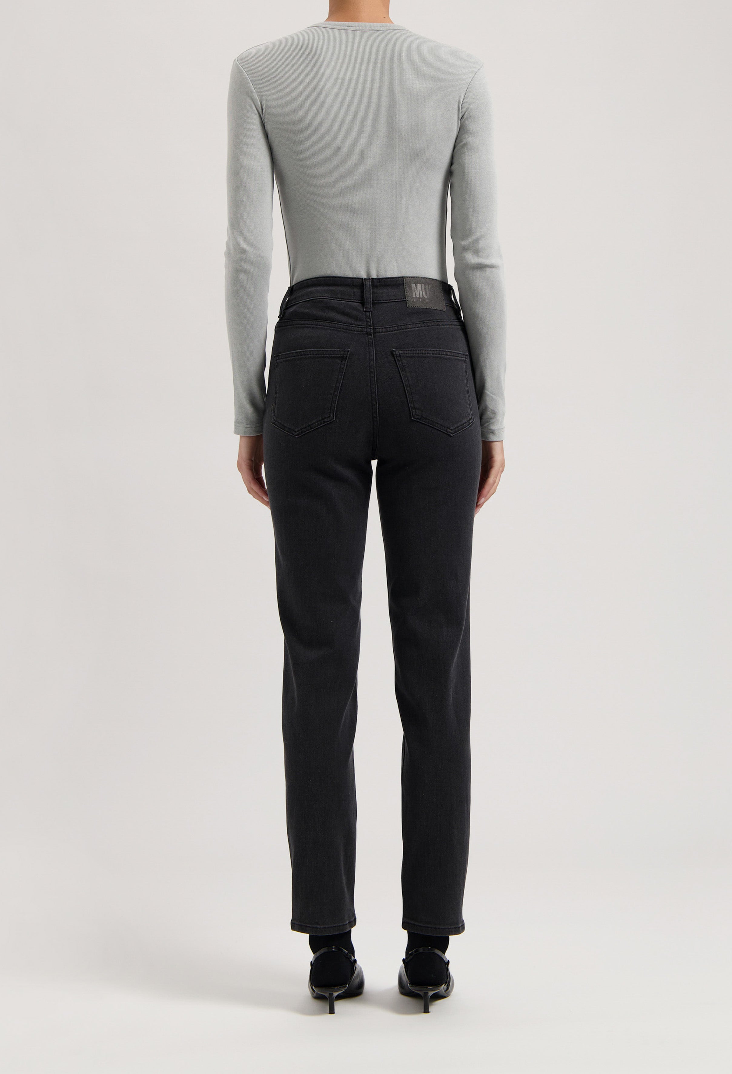 Light gray long-sleeve top paired with modern black denim jeans, showcasing a sleek and minimalist casual look.