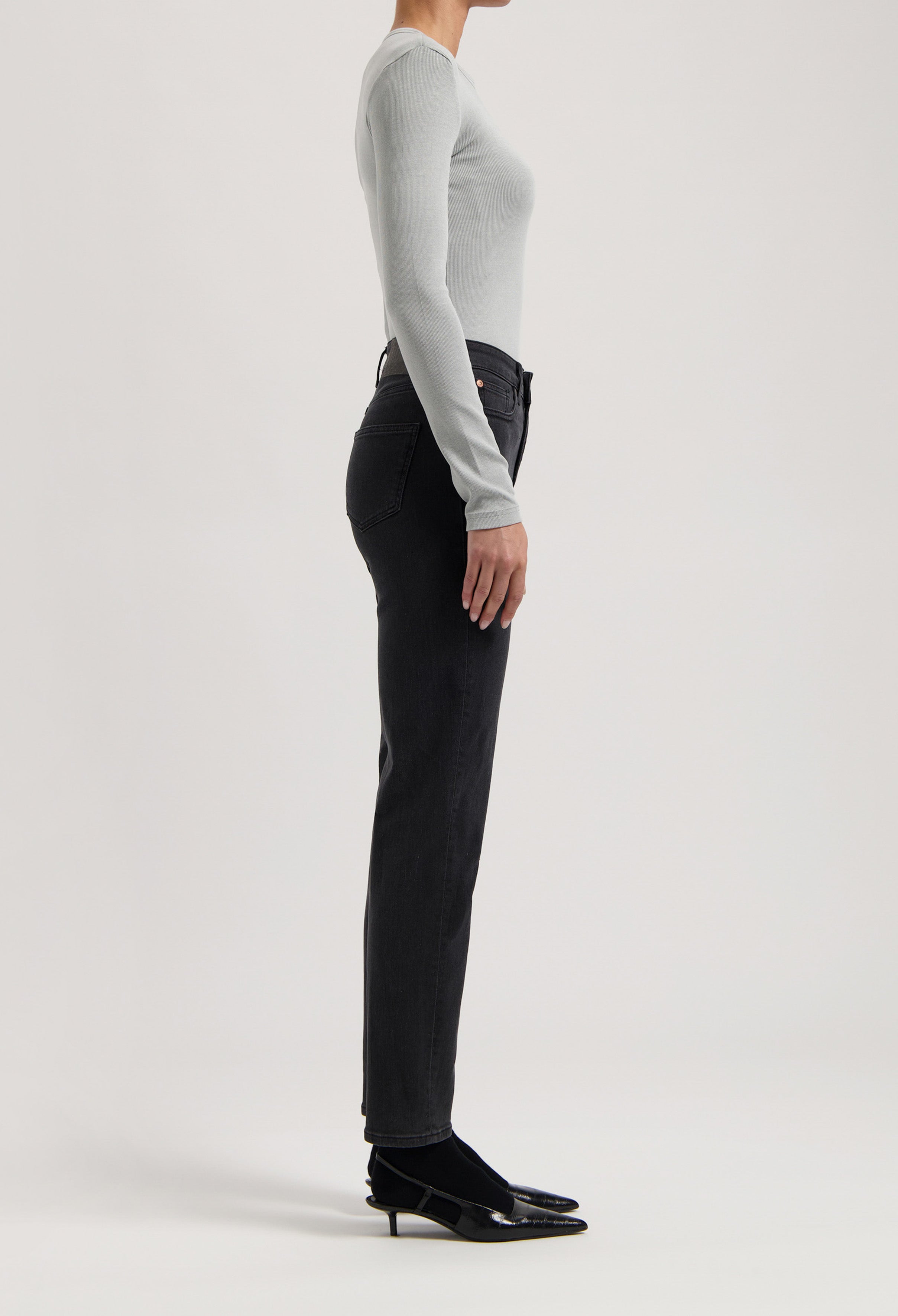 Gray long-sleeve top paired with black high-waisted jeans, side view showcasing sleek silhouette and elegant style.