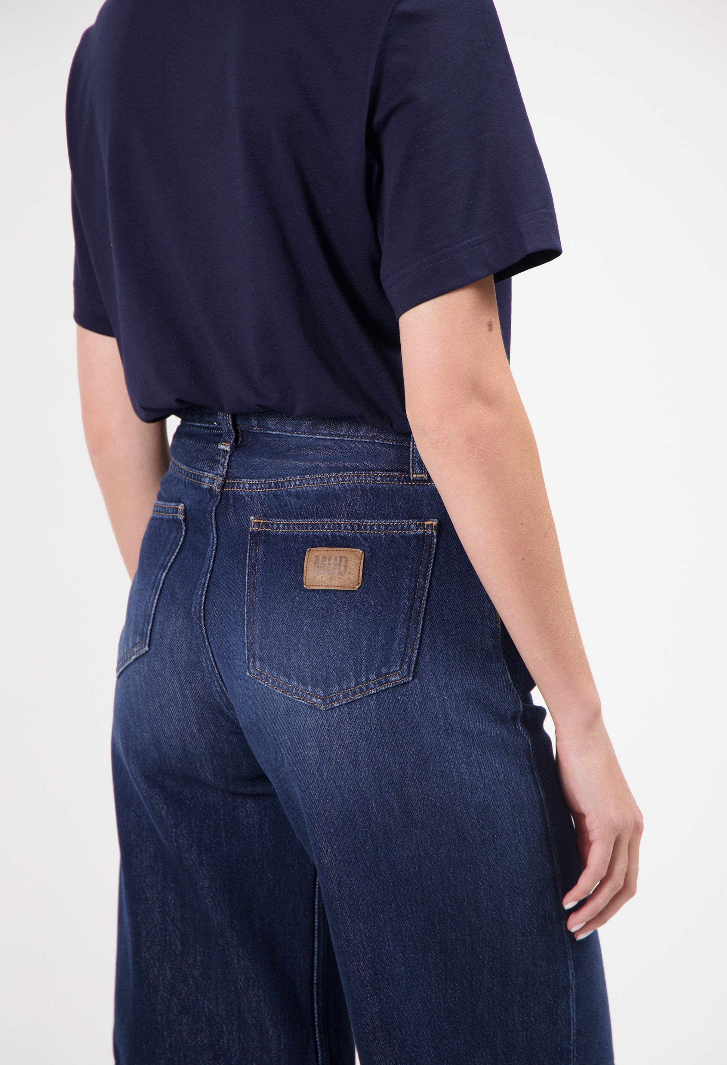 Dark blue wide-leg MUD Jeans made from organic cotton, showcasing a back view paired with a black short-sleeve top.