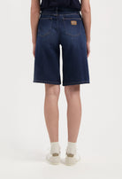 Back view of dark blue MUD Jeans denim shorts, showcasing high-waisted design with two pockets, paired with a navy top.