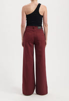 Wide-leg burgundy jeans made from sustainable organic cotton, paired with a modern black one-shoulder tank top.