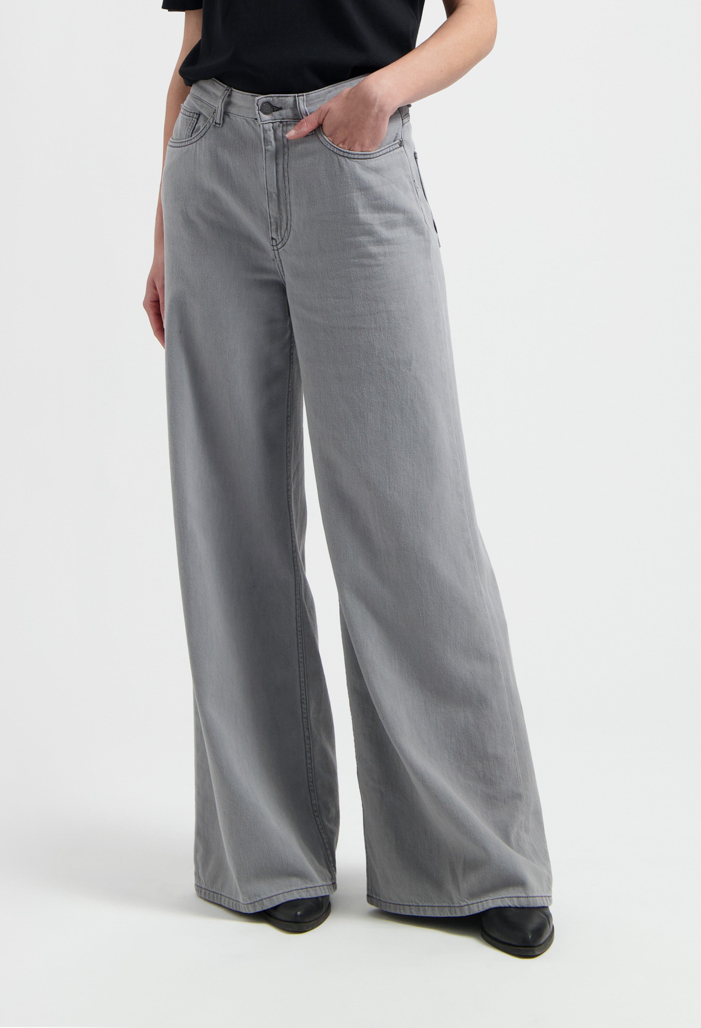 Wide-leg gray jeans made from denim, showcasing a high-waisted design paired with a black top, emphasizing casual style.