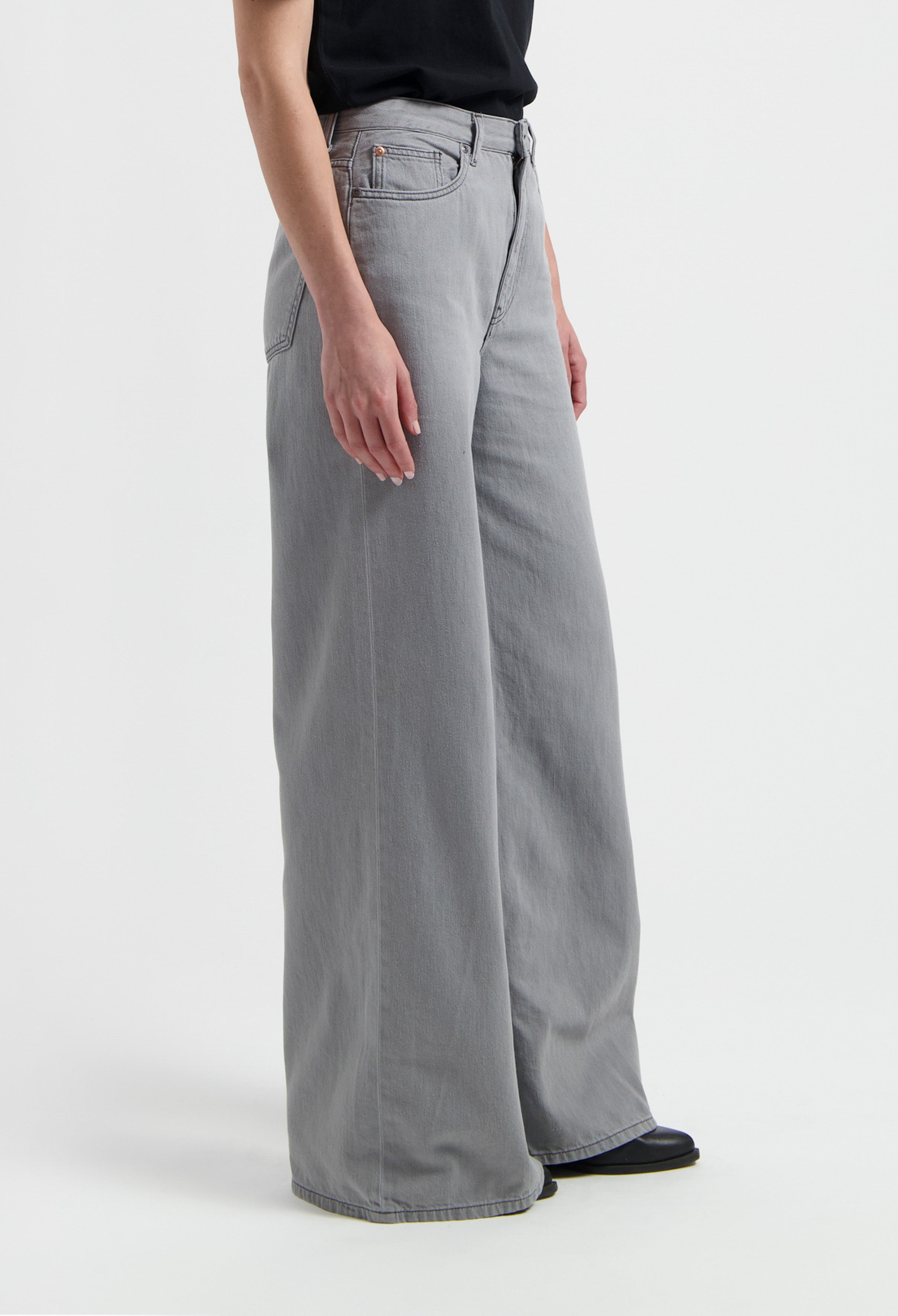 Wide-leg gray denim pants with a high waist, paired with a black top, showcasing minimalist casual fashion style.