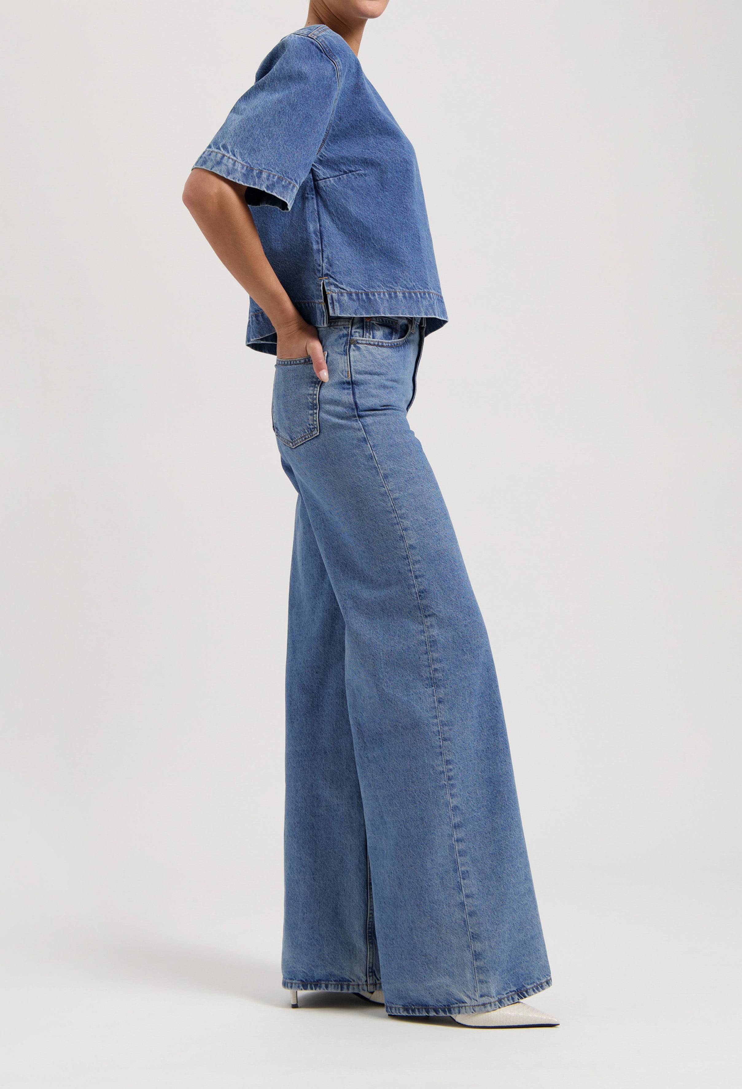 Wide-leg denim jeans paired with a loose short-sleeve denim top, creating a relaxed casual outfit on a neutral background.