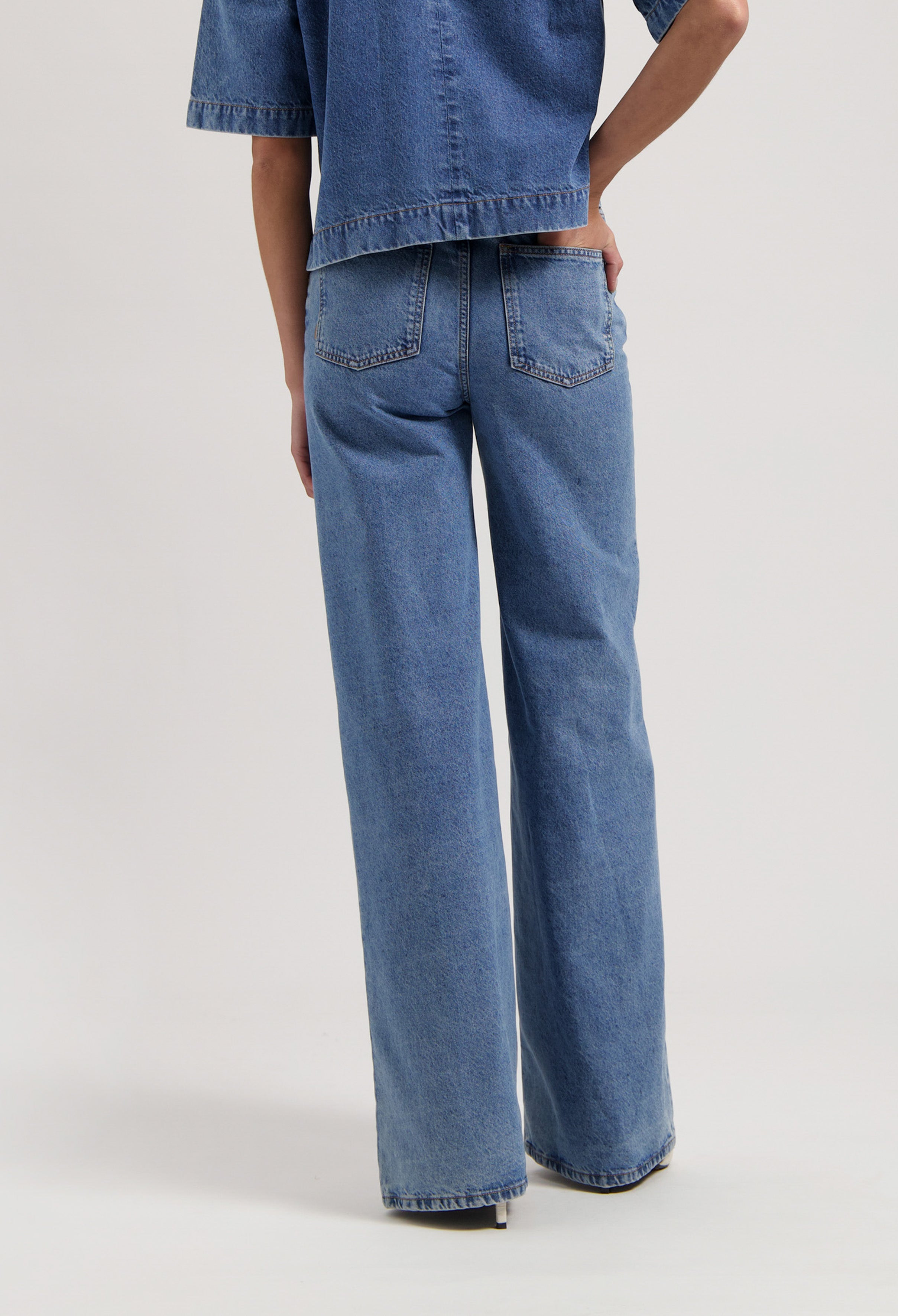 Wide-leg blue denim jeans, featuring a high waist and classic back pockets, paired with a matching denim short-sleeve top.